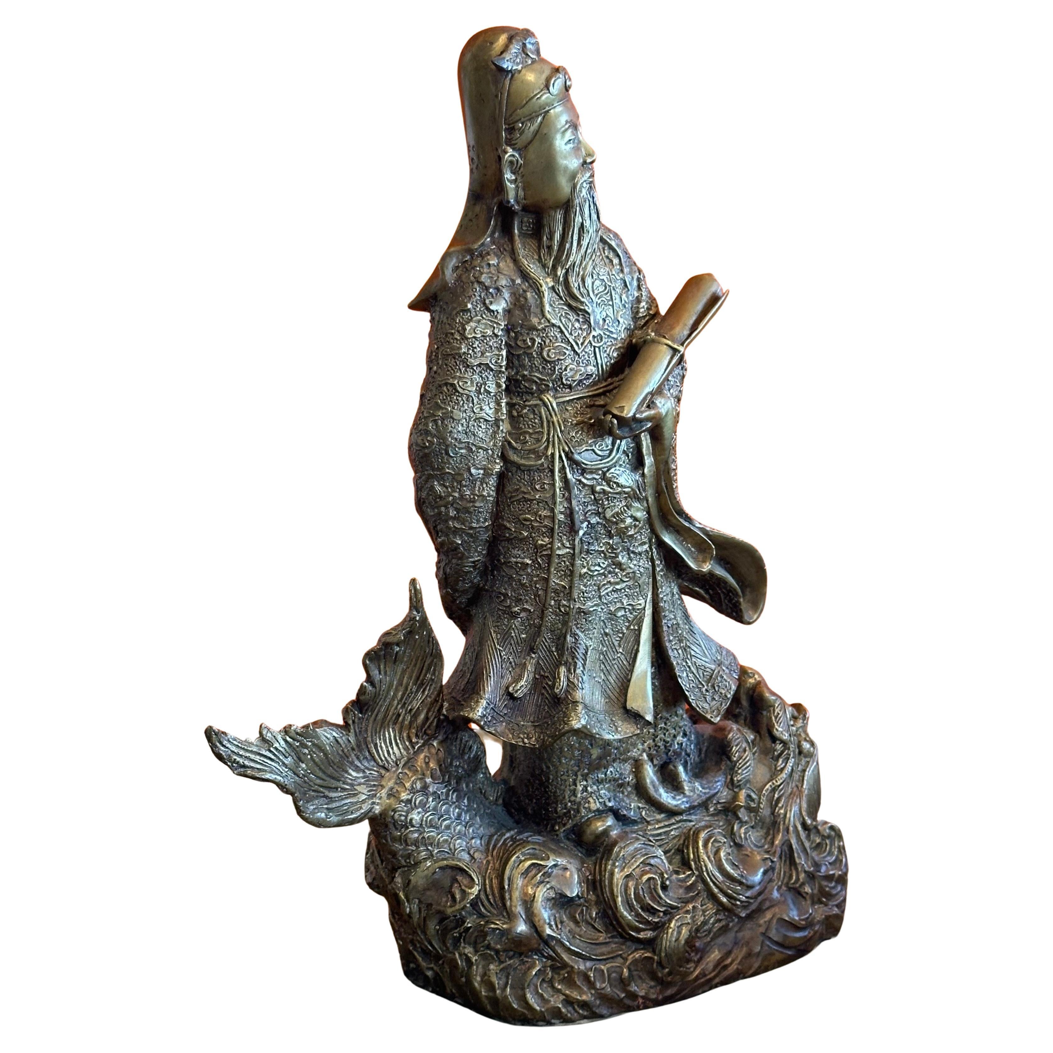  Una figura ancestral china muy bonita / estatua de un dios (posiblemente Fu Xing; dios de la prosperidad) en bronce fundido, hacia la década de 1950.  La escultura representa a la figura de pie sobre un gran pez o criatura marina.  La pieza está en