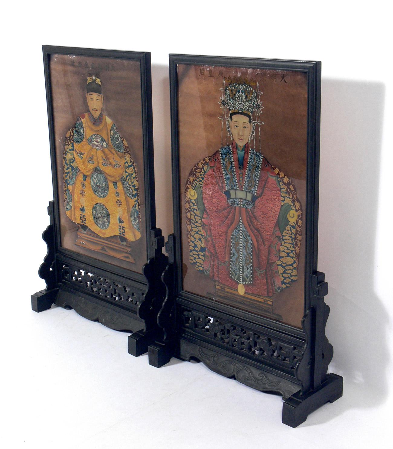 Chinese ancestral reverse paintings on glass, China, 20th century. We are unsure of the age on these. Probably mid-20th century, possibly much earlier. They retain their original hand carved wood stands. One glass has a crack at the bottom right,