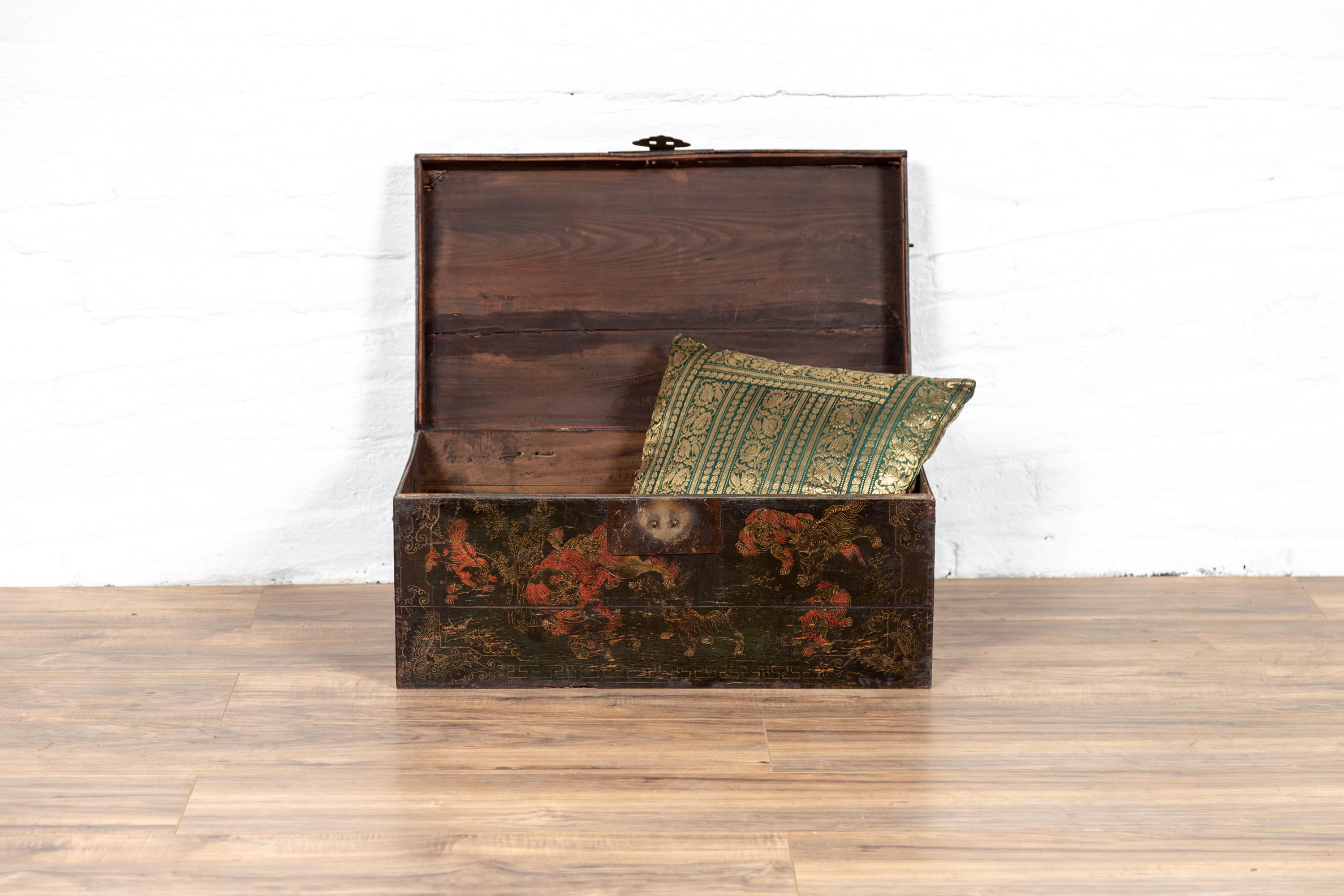 A Chinese antique black lacquer rectangular blanket chest from the 19th century, with underglaze décor and hand painted guardian lions. Born in China during the 19th century, this elegant wooden box features a linear Silhouette, perfectly decorated