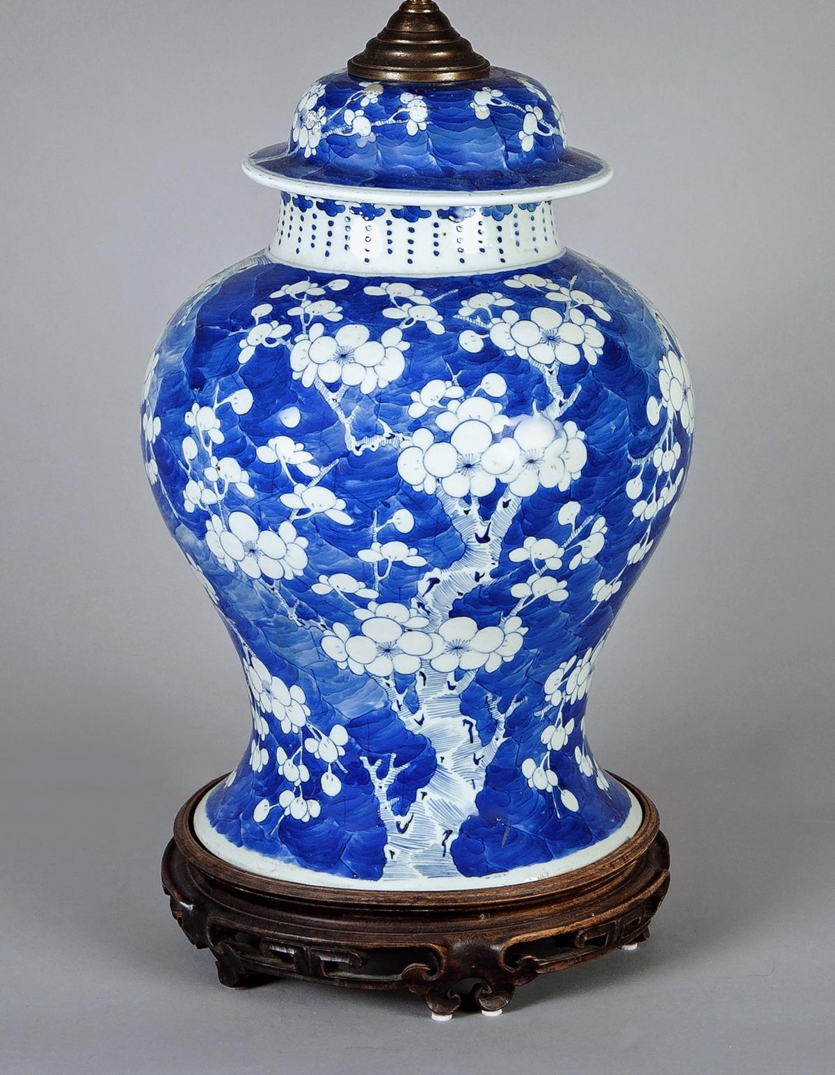 Large Chinese blue and white porcelain baluster form covered vase lamp decorated with prunus flowering branches on crackled ice ground mounted on a carved hardwood antique base.