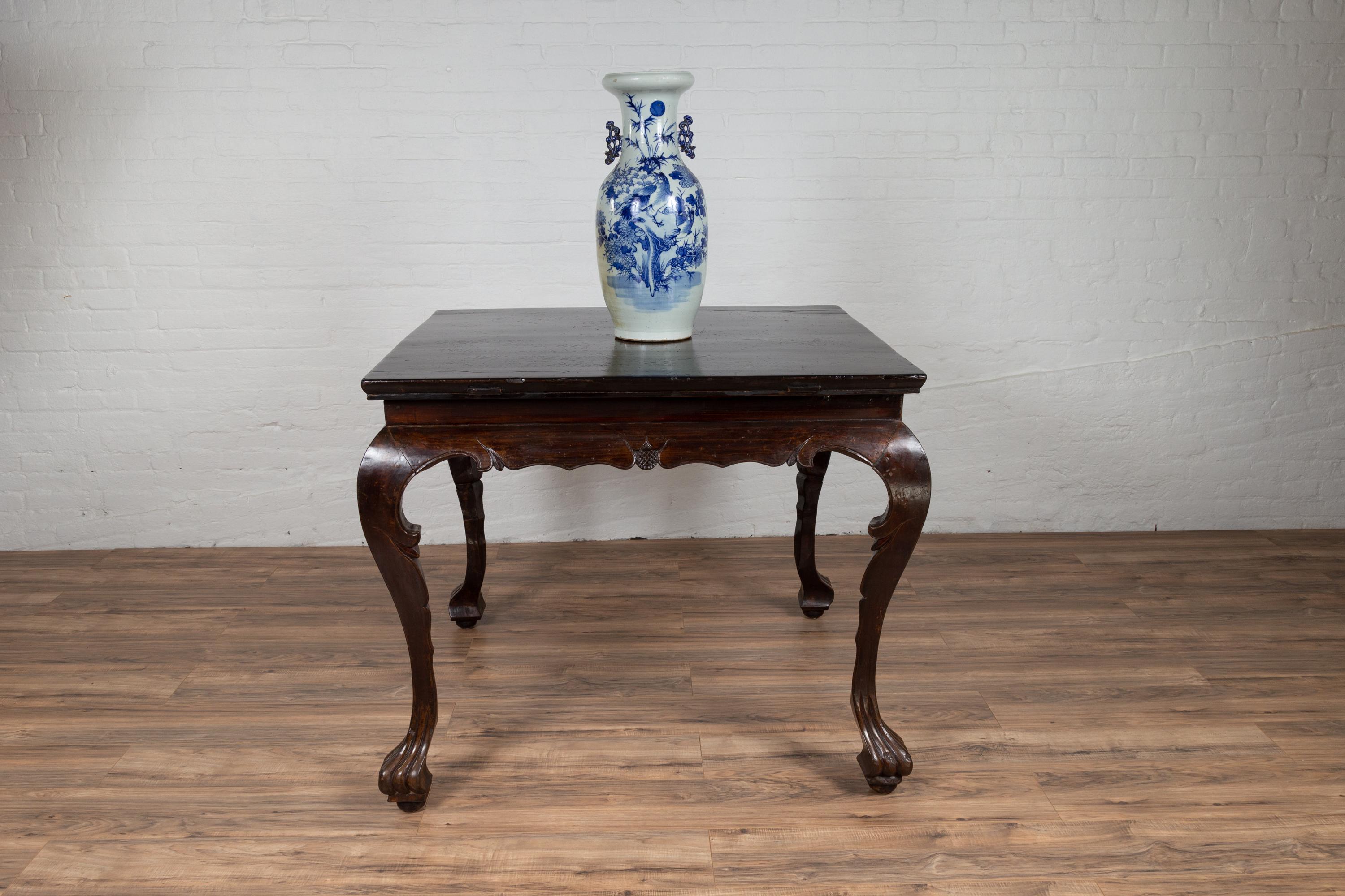 A Chinese antique center hall table from the early 20th century, with black lacquered top and brown stained legs. Born in China during the early years of the 20th century, this lovely center table features a black lacquered rectangular top with