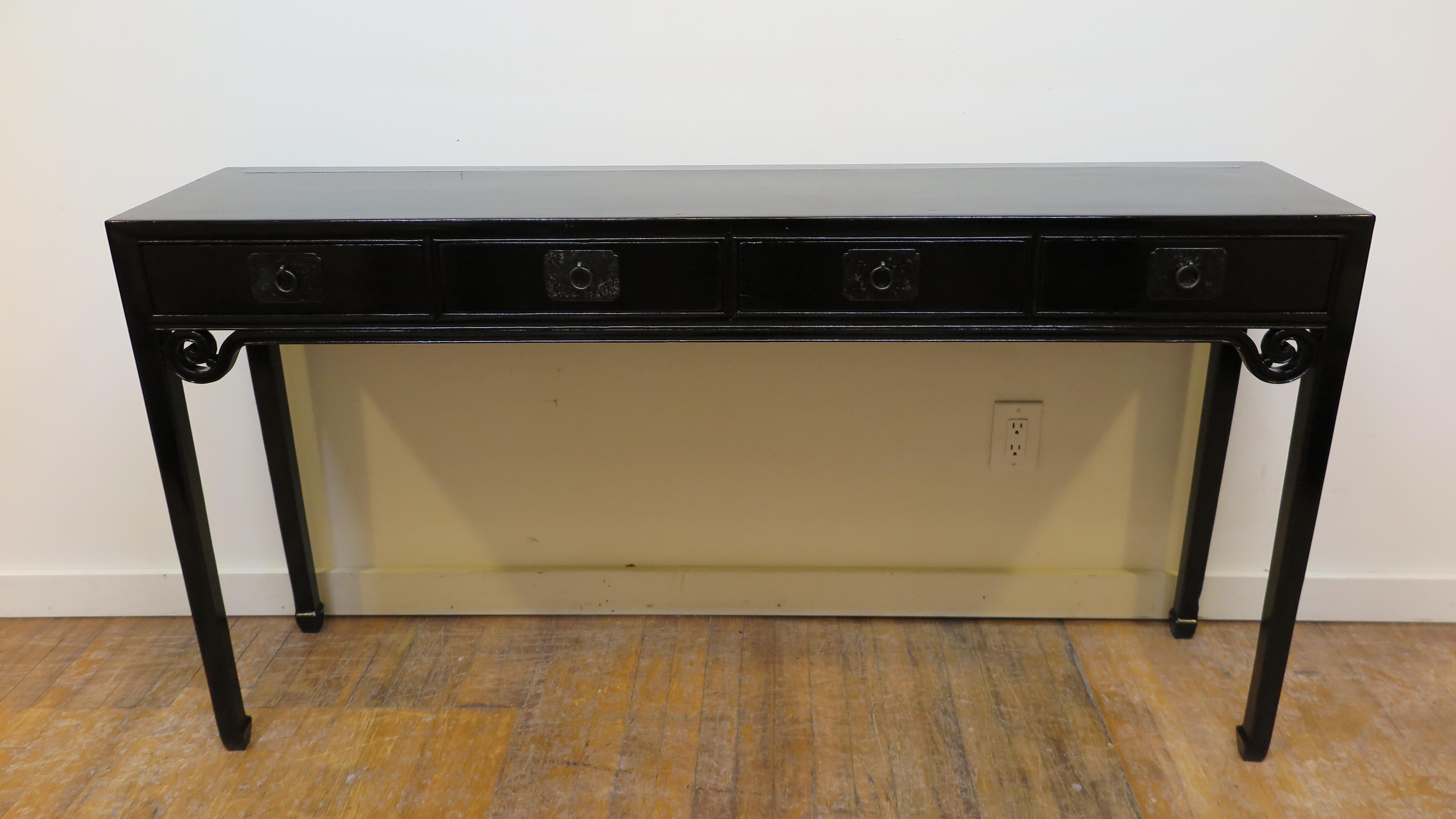 Antique Chinese black lacquer console table. Four drawer console table having scroll spandrel apron detail on tapered legs terminating to horse hoof feet. Minimal clean lines solid elmwood showcased in black lacquer. A very elegant functional