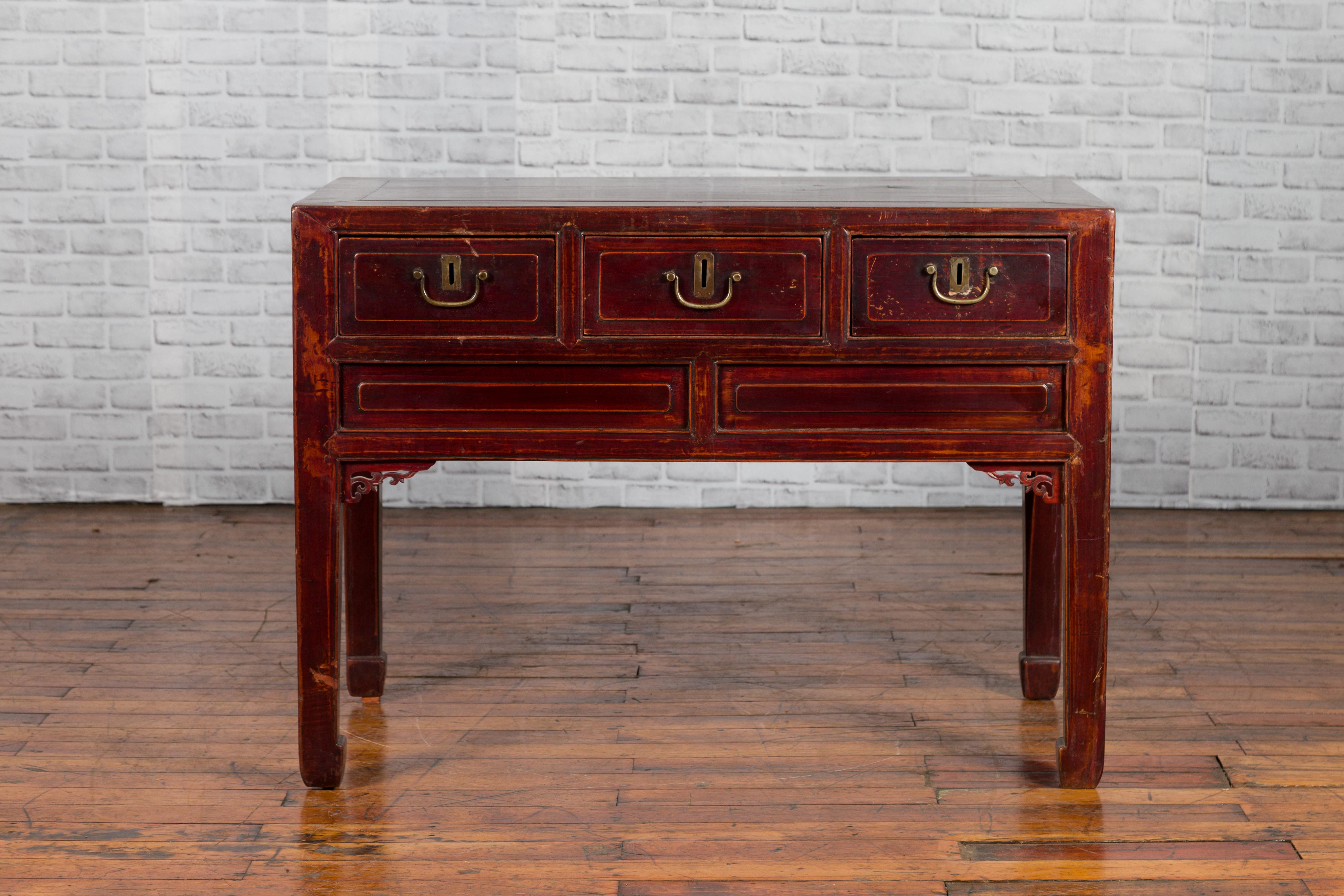 A Chinese antique console table from the early 20th century, with three drawers and carved spandrels. Crafted in China, this 100 years old console table features a rectangular top with central board, sitting above three drawers fitted with brass