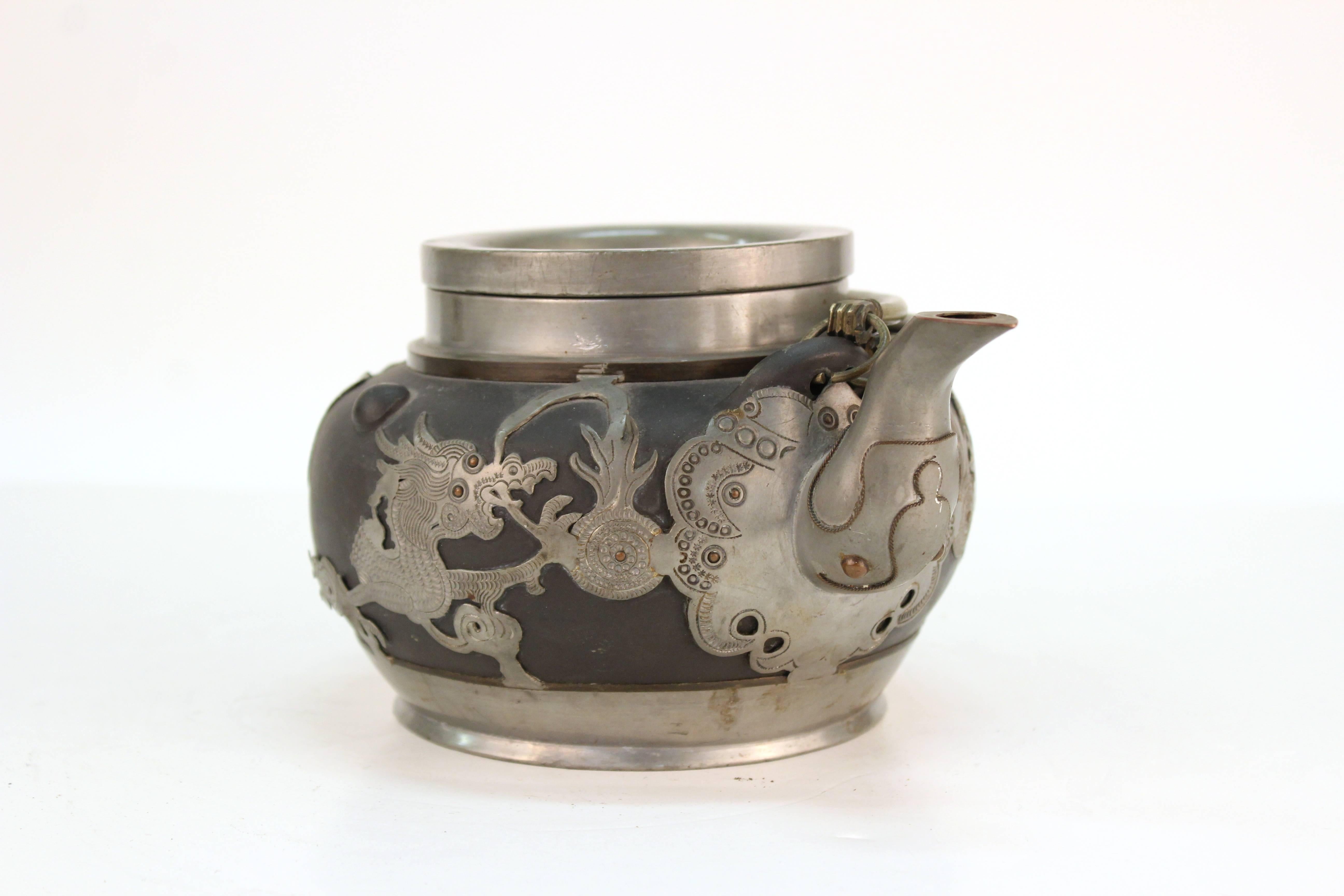 Chinese antique earthenware and pewter teapot, with dragon motif and metal handles. The piece is stamped illegibly on the bottom and is in good vintage condition.
