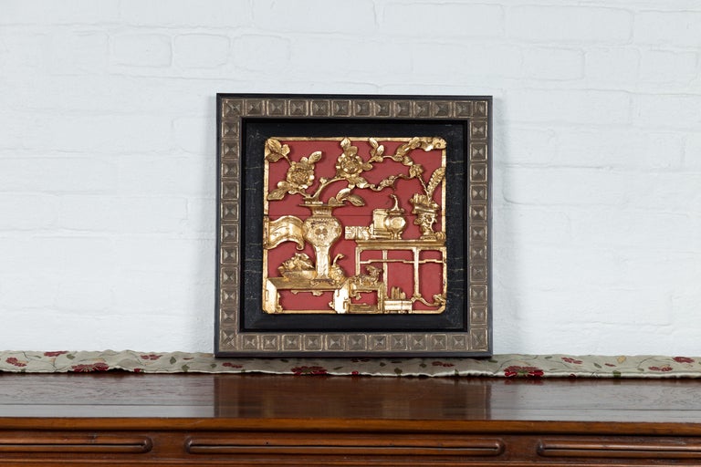 An antique Chinese giltwood architectural panel on red ground, with floral motifs, set in new frame. This Chinese architectural panel features an exquisite carved giltwood decor, depicting an interior adorned with a Ming style waisted table with