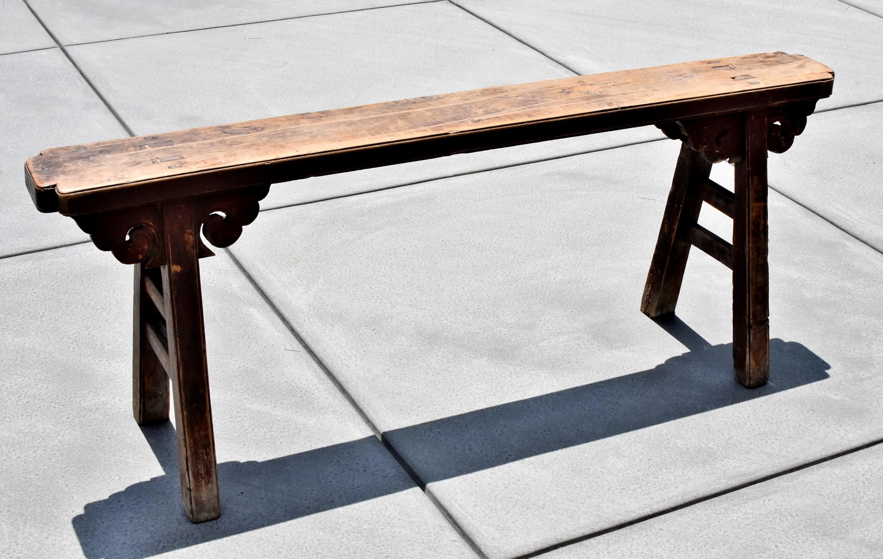 A 19th century Chinese antique bench with solid single-board top and scrolled 