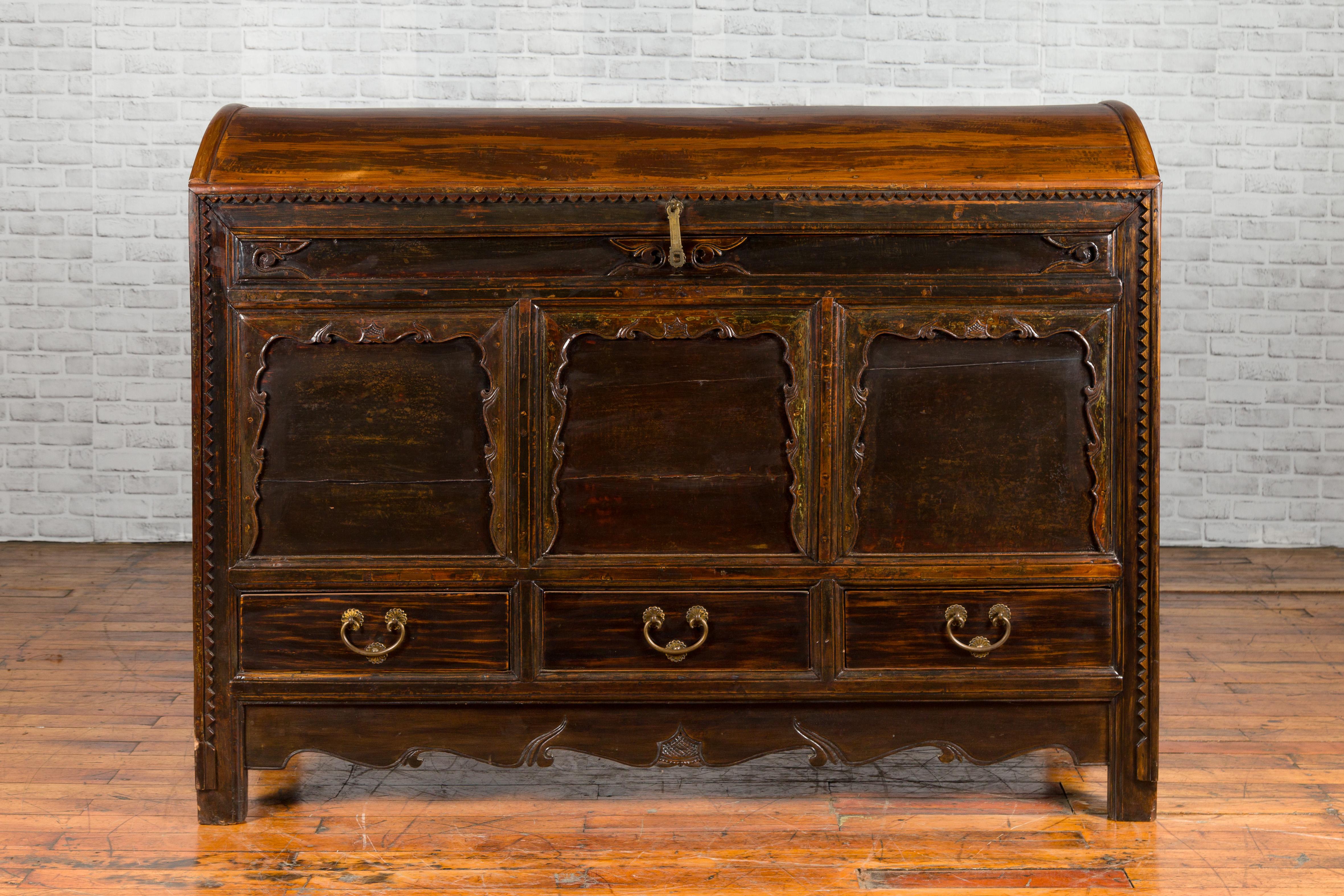 A Chinese antique dowry chest from the early 20th century, with carved panels, three drawers and scalloped skirt. Created in China during the early years of the 20th century, this dowry chest features a dark patina perfectly complimenting the