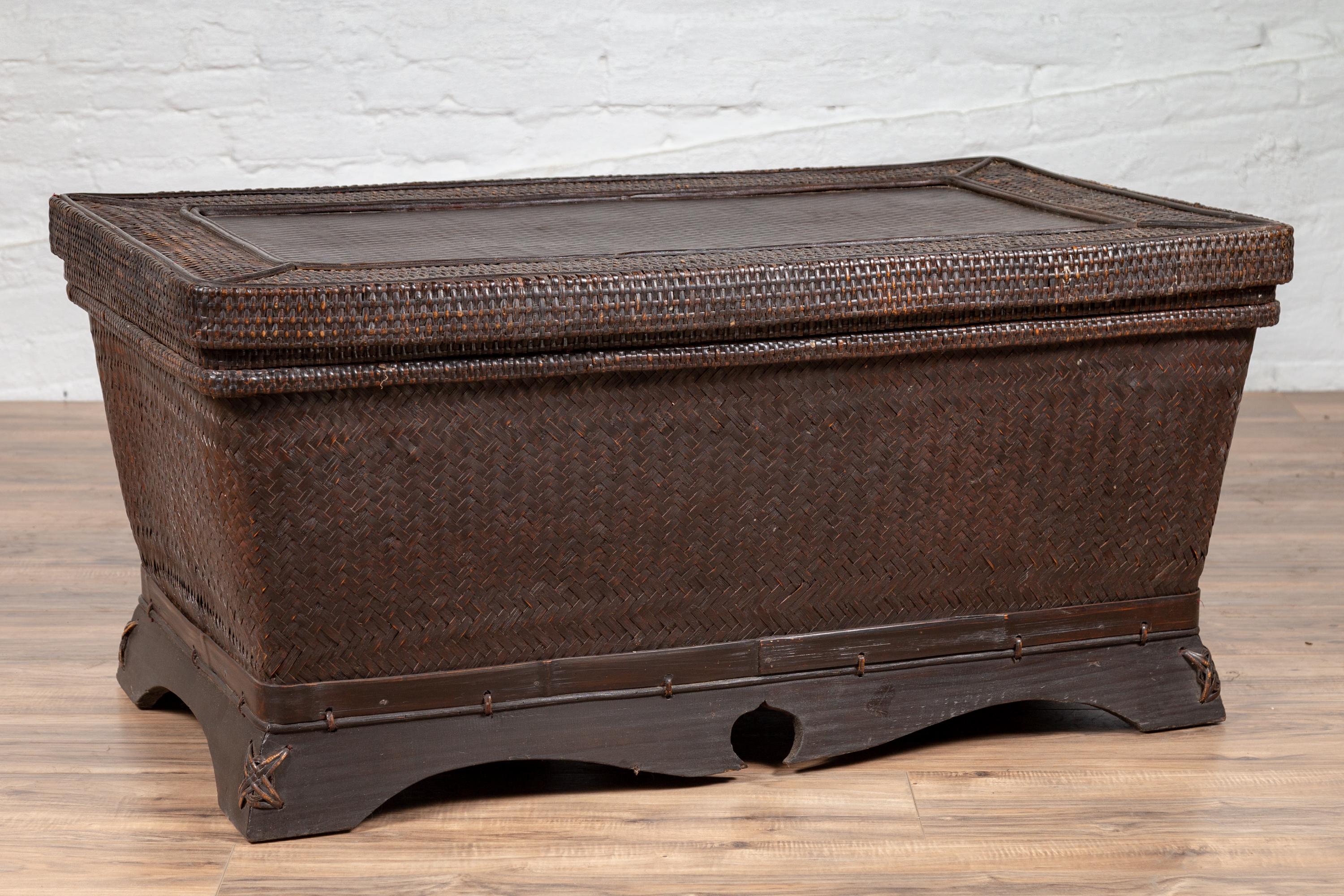 A Chinese antique basket coffee table from the early 20th century, made of dark brown woven rattan over wood. Born in China during the early years of the 20th century, this charming basket will make for an excellent coffee table. Presenting woven