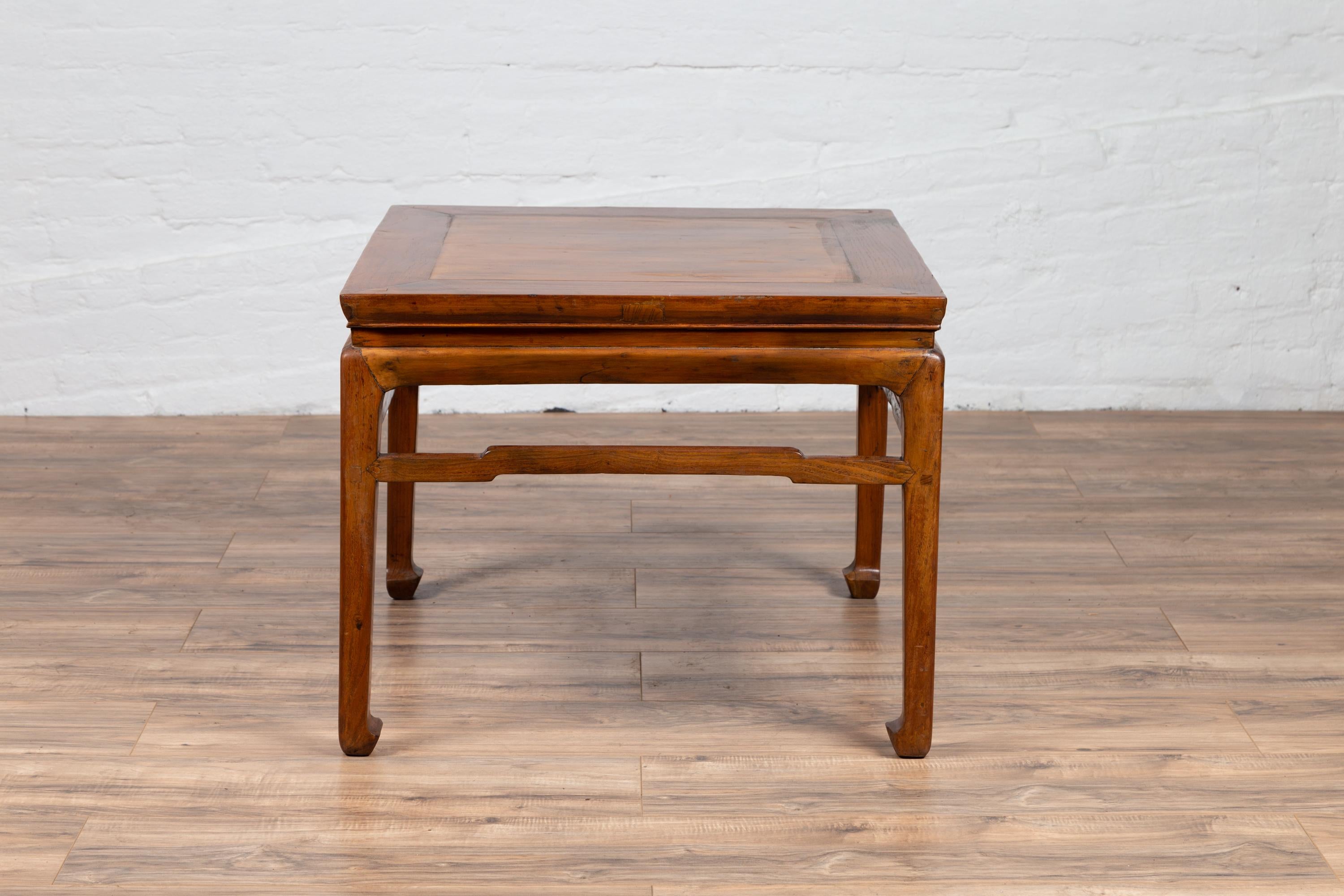 A Chinese antique Ming Dynasty style side table from the early 20th century, with horse hoofed feet and humpback side stretchers. Born in China during the early years of the 20th century, this elegant Ming Dynasty style side table features a square
