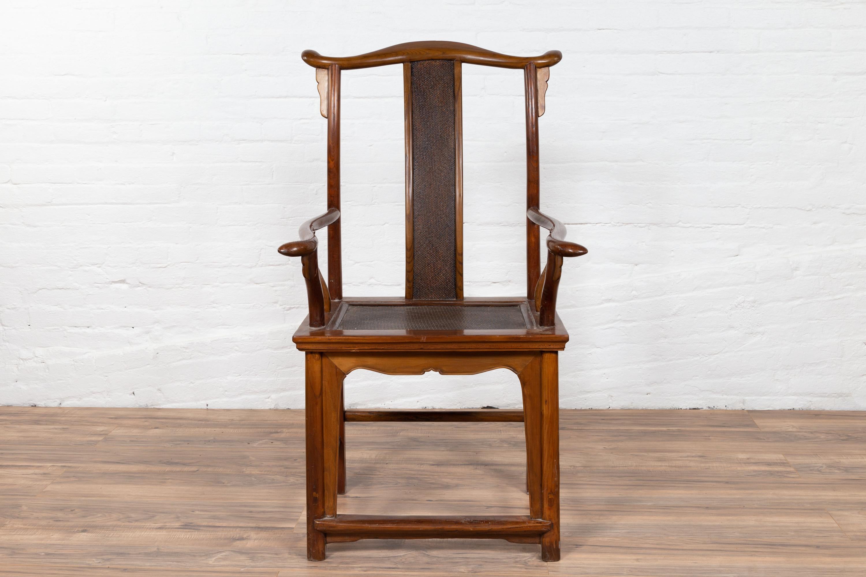 A Chinese Ming Dynasty style antique scholar's chair from the early 20th century, with inset rattan back splat and seat. Born in China during the early years of the 20th century, this exquisite wooden armchair features an elegant tall back, topped