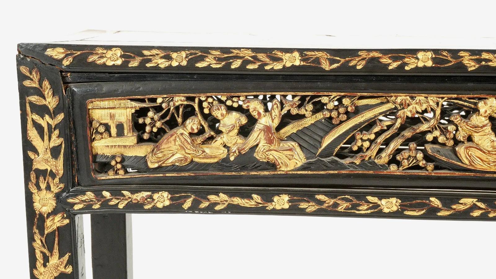 An early 20th century Chinese parcel-gilt altar console table with hand carved décor, This Chinese console table features parcel gilt reticulated skirt panels with figures in landscapes, thin gilded frieze showcasing a delicate scrollwork