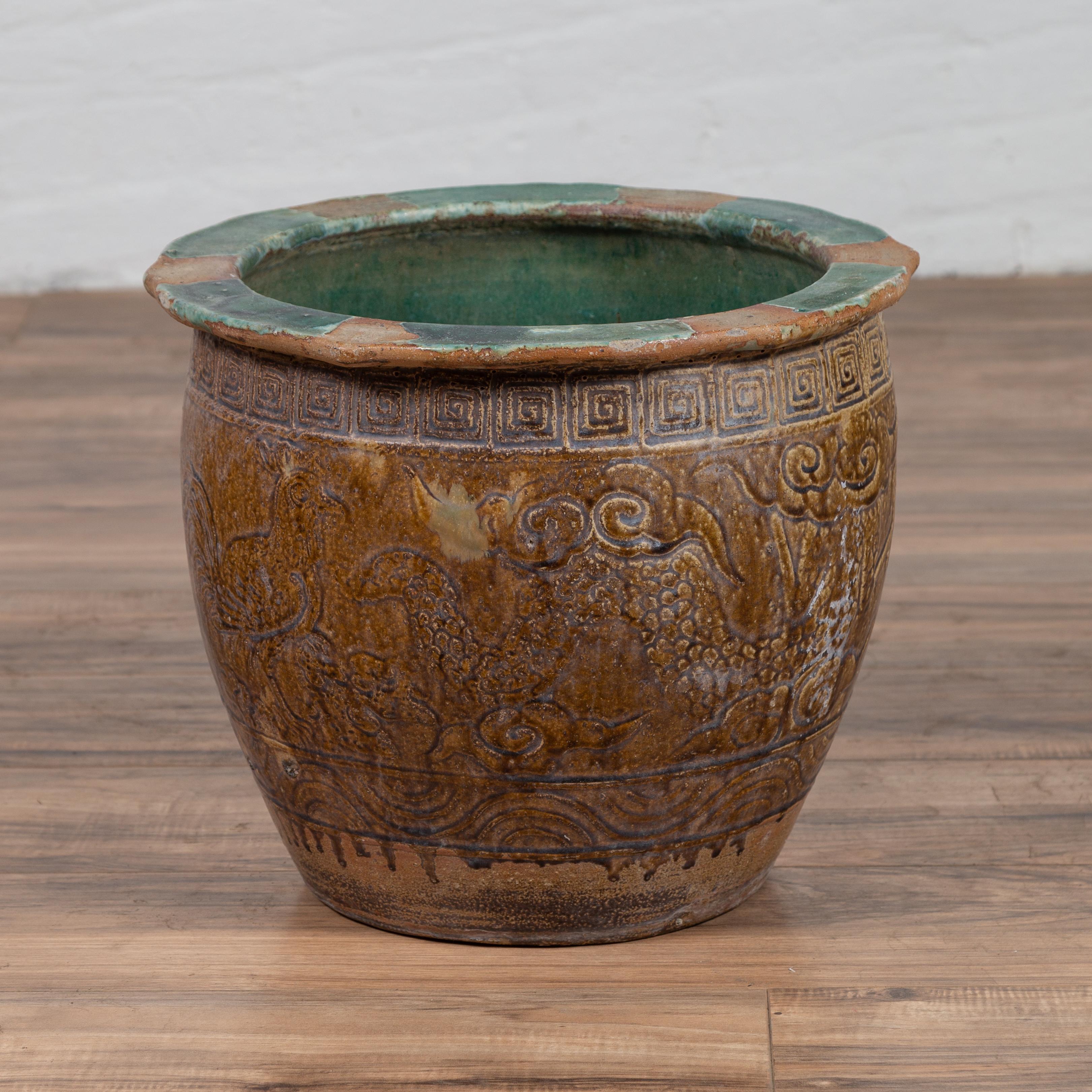 A Chinese antique planter from the early 20th century with weathered patina, green and brown glaze, meanders, animals and scrolled clouds. Born in China during the early years of the 20th century, this large planter charms us with its nicely aged