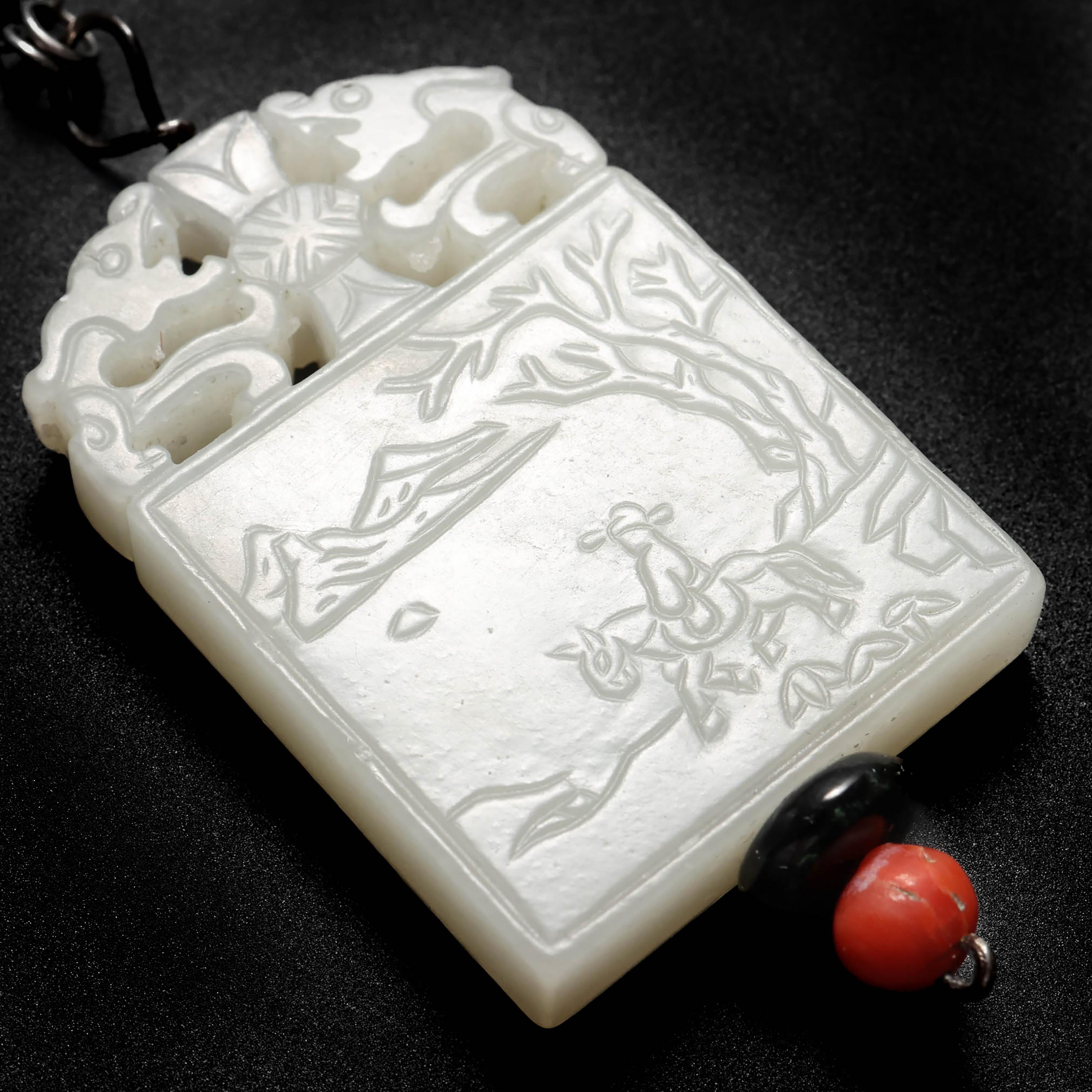 Elegante, rara y de finales del periodo Qing (hacia la década de 1890), esta placa de nefrita blanca casi incolora, tallada a mano, está grabada por ambas caras. En una de ellas, la figura mitológica china conocida como Zhang Guo Lao aparece montada