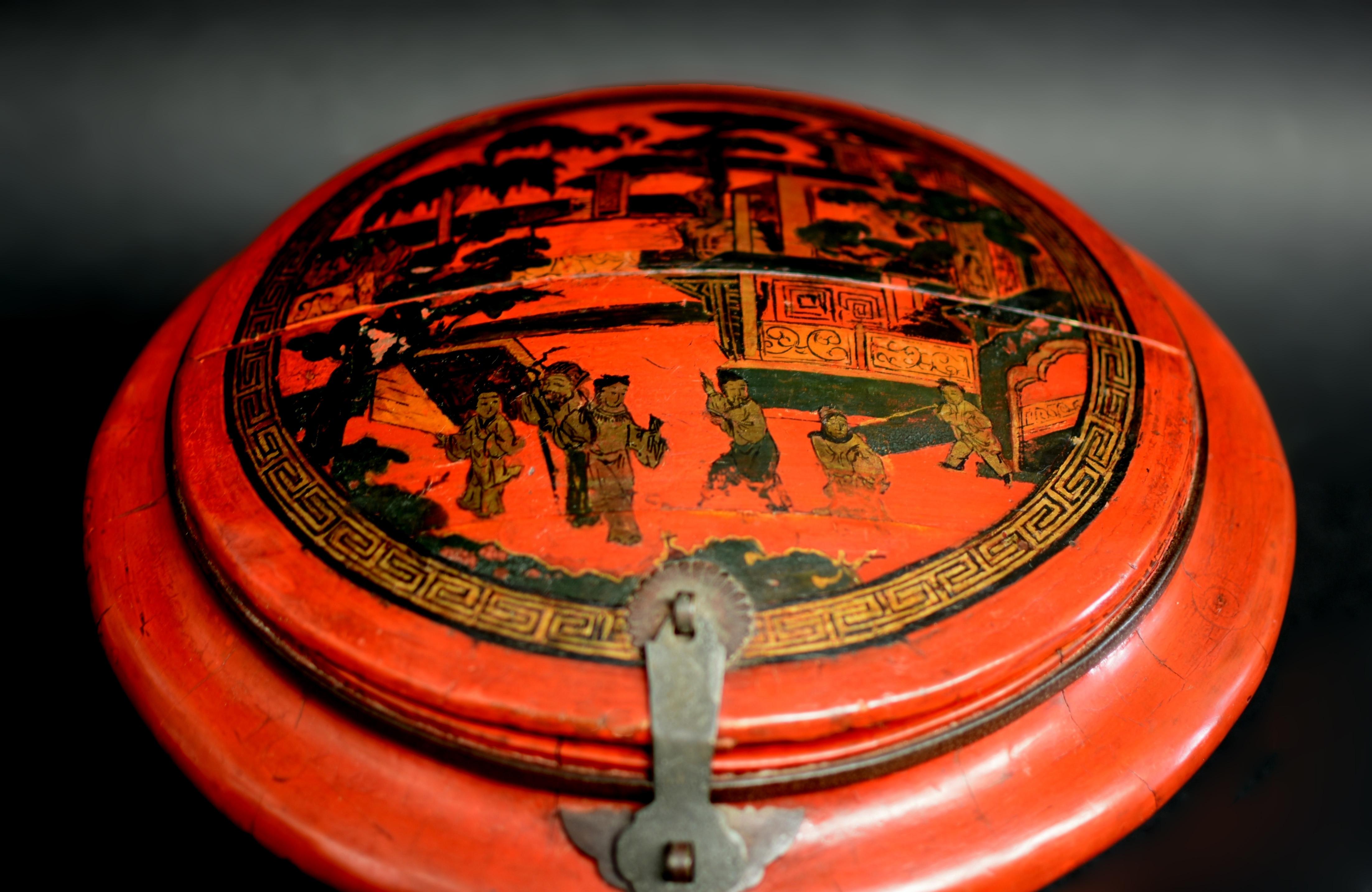 A finely made, 19th century Chinese red lacquer basket in remarkable original condition. Of round form with painted cover depicting a scene in the imperial garden with pavilions in depth and verdant trees. The figures are a senior official and his