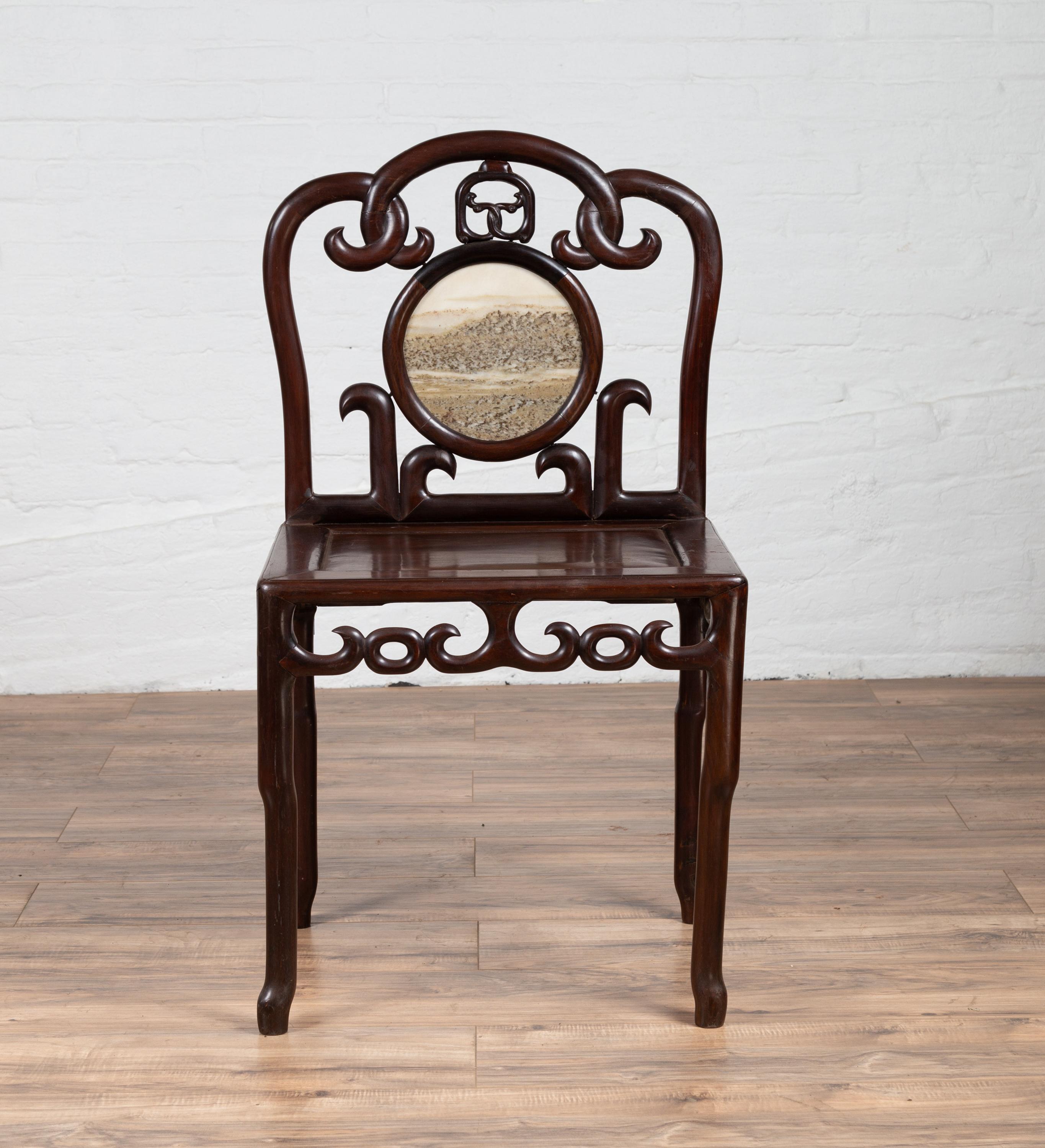 An antique Chinese rosewood side chair from the early 20th century, with marble medallion inlay and open fretwork. Born in China during the early years of the 20th century, this exquisite side chair captivates us with its fretwork design, dark