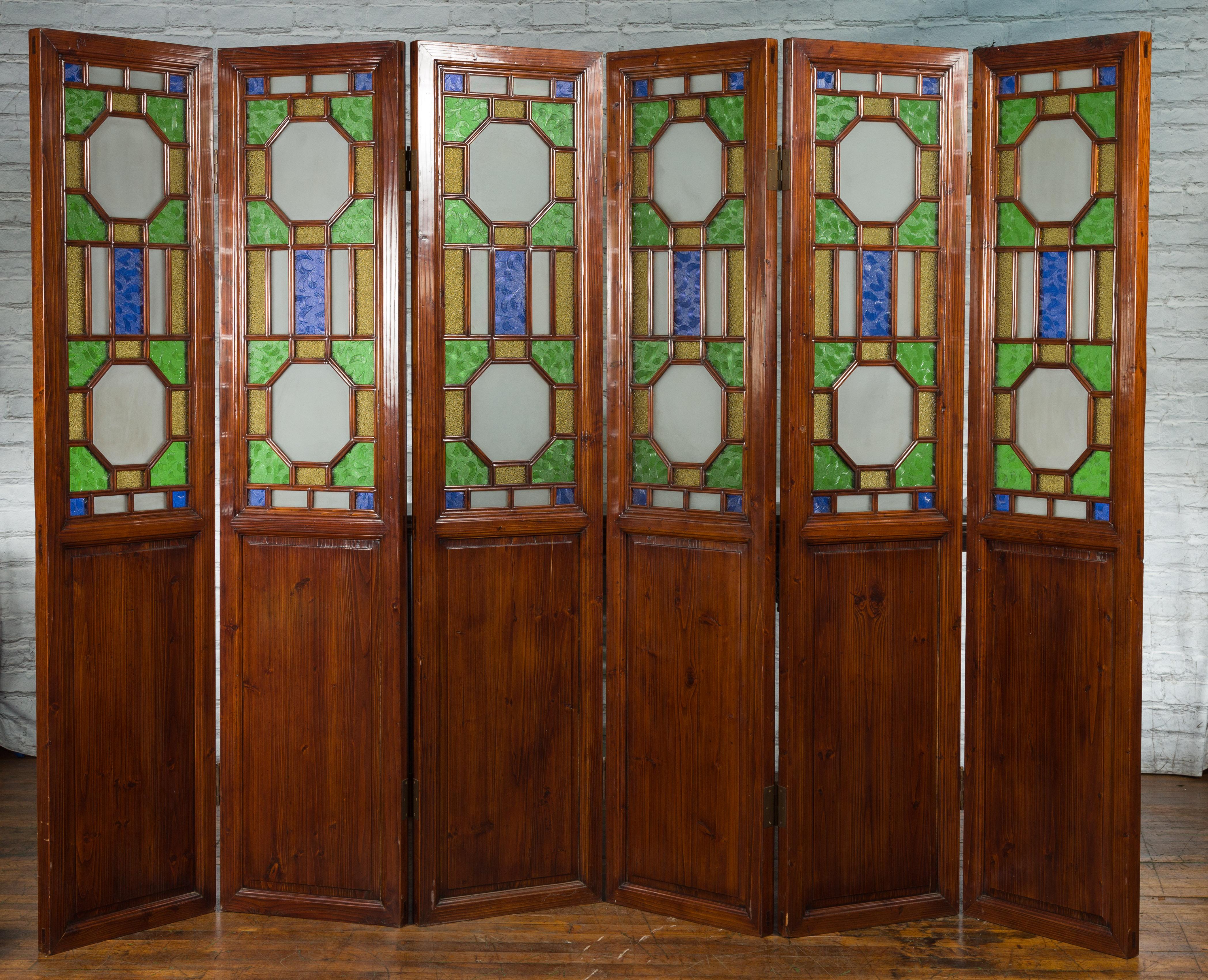 A Chinese antique six-panel folding screen from the early 20th century, with green, blue and yellow stained glass, geometric motifs and wooden panels. Created in China during the first half of the 20th century, this large folding screen features six