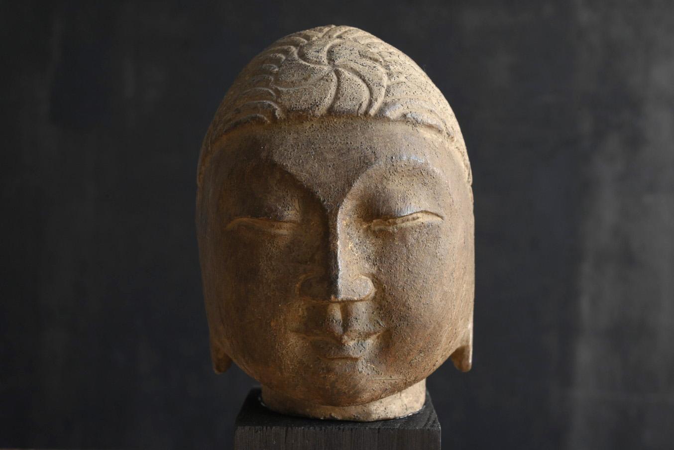 This is an old Buddha head made in China.
It dates from before the 19th century and may be even older.
The face of this Buddha's head is neat and beautifully symmetrical.The mouth is tightly pursed, the bridge of the nose is straight, and the