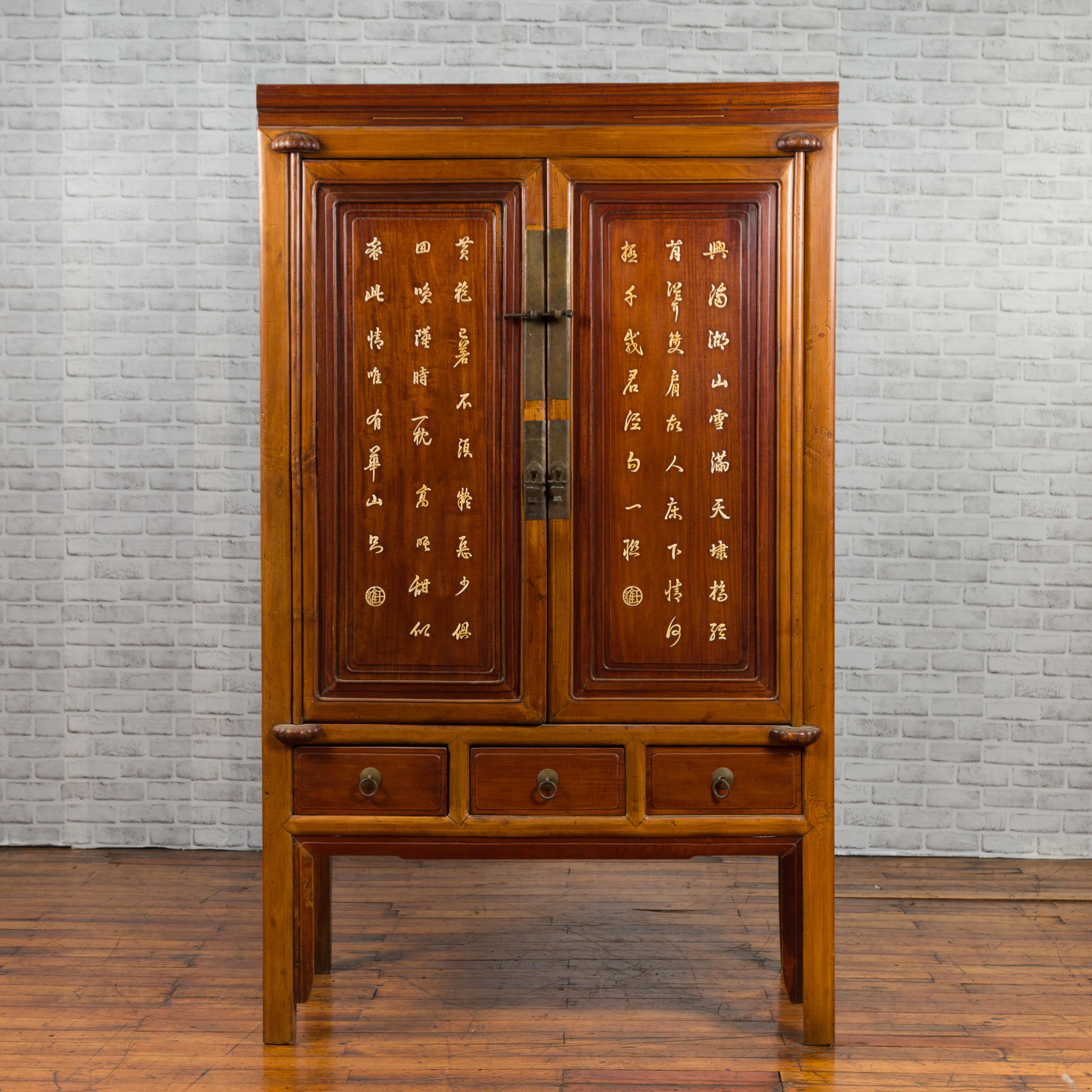 A Chinese antique cabinet from the 20th century, with inlaid calligraphy motifs, inner shelves and drawers. Created in China during the 20th century, this antique cabinet features an elegant two-toned façade adorned with golden inlaid calligraphy