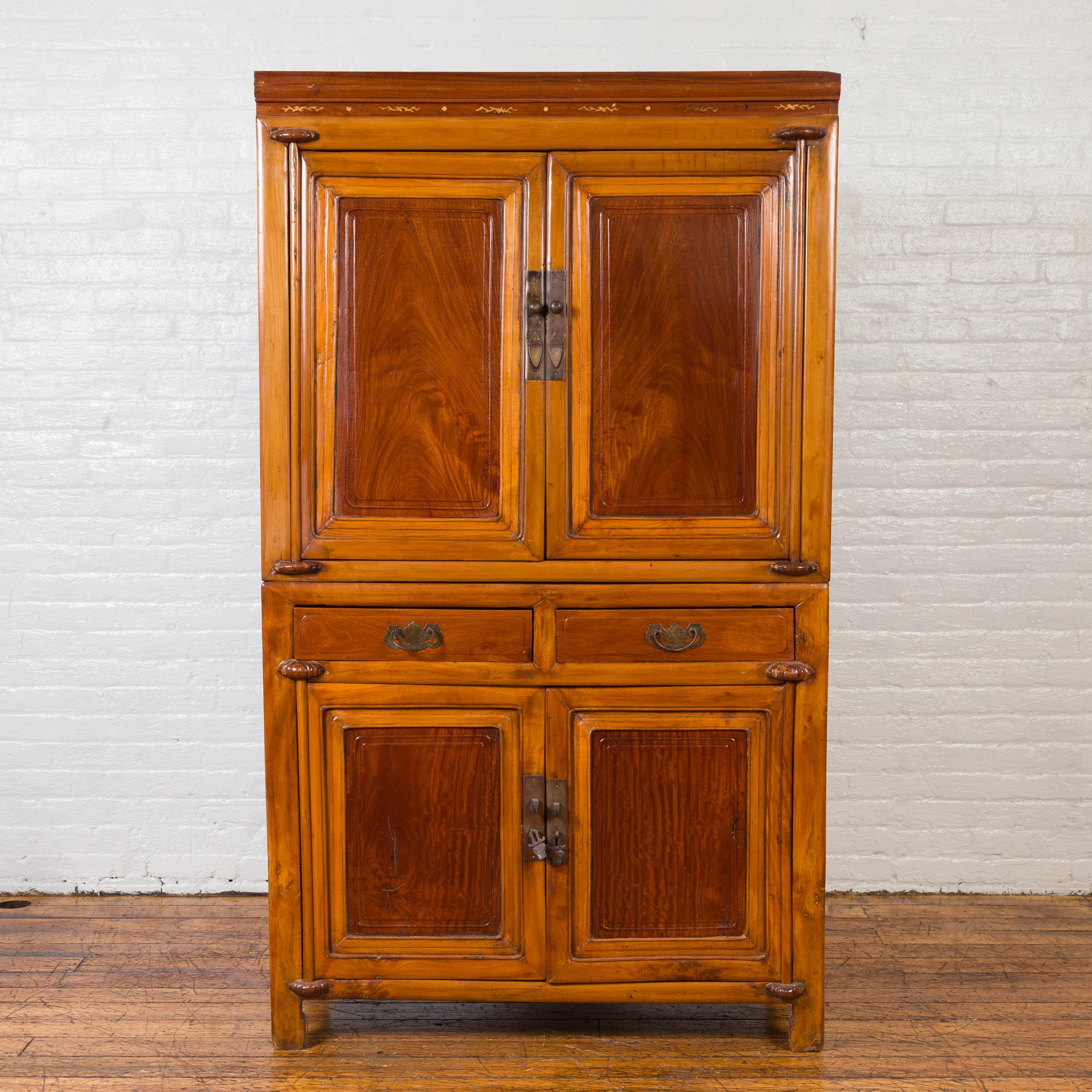 An antique Chinese two-toned stacking cabinet from the early 20th century, with doors and drawers. Found in Taiwan, this Chinese cabinet attracts our attention with its two-toned patina that highlights the panelled doors beautifully. Presenting a
