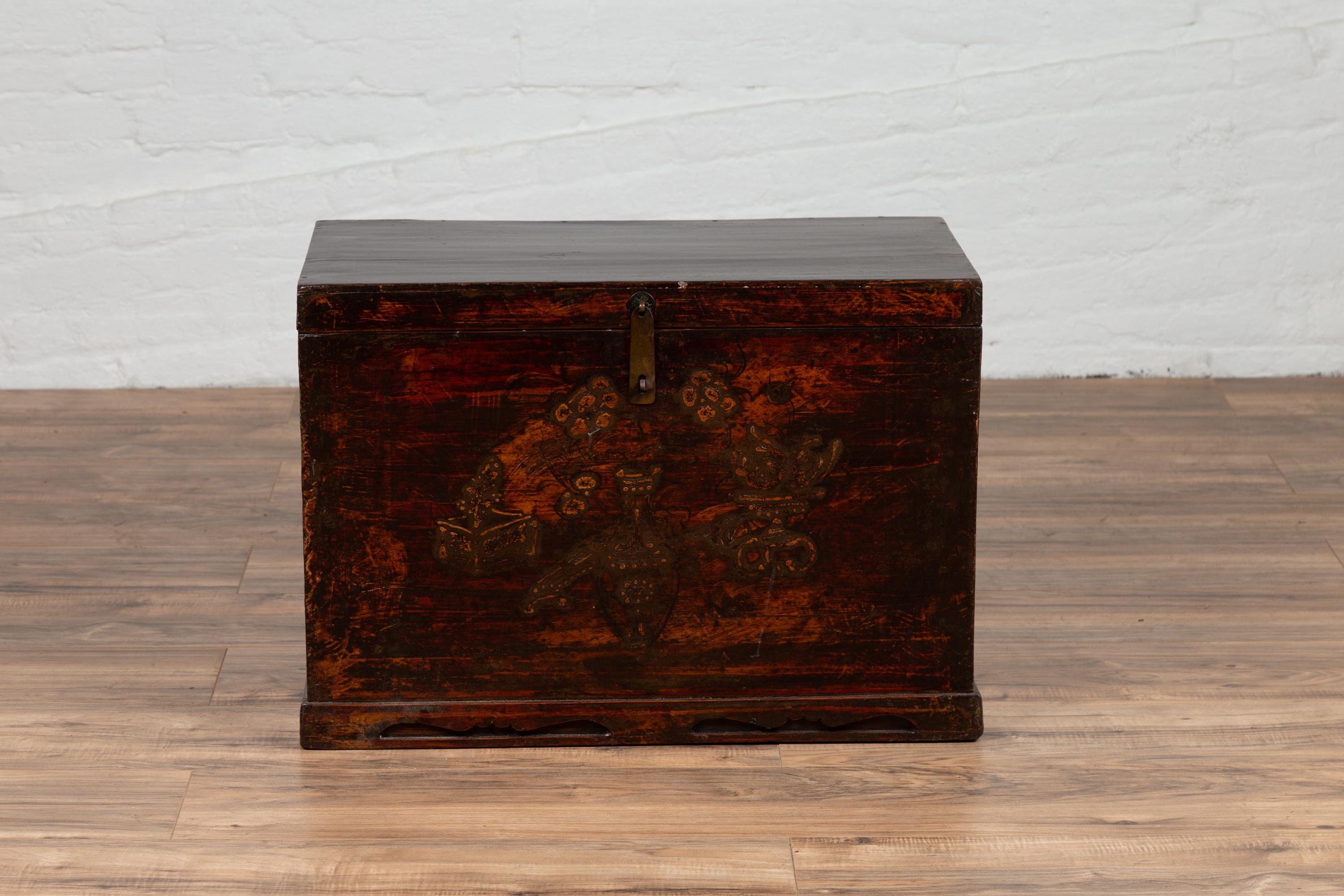 A Chinese antique blanket chest from the early 20th century, with raised decor, polychrome patina and brass hardware. This exquisite Chinese blanket chest features a rectangular lid resting upon a lovely façade, adorned with raised motifs. The lid