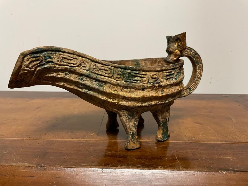 Chinese archaic style gilt bronze pouring vessel with dragon headed handle and geometric decoration. With wonderful gilt and verdigris patina. The boat form vessel with single loop handle supported on four legs. 
Great decorative item, or unusual