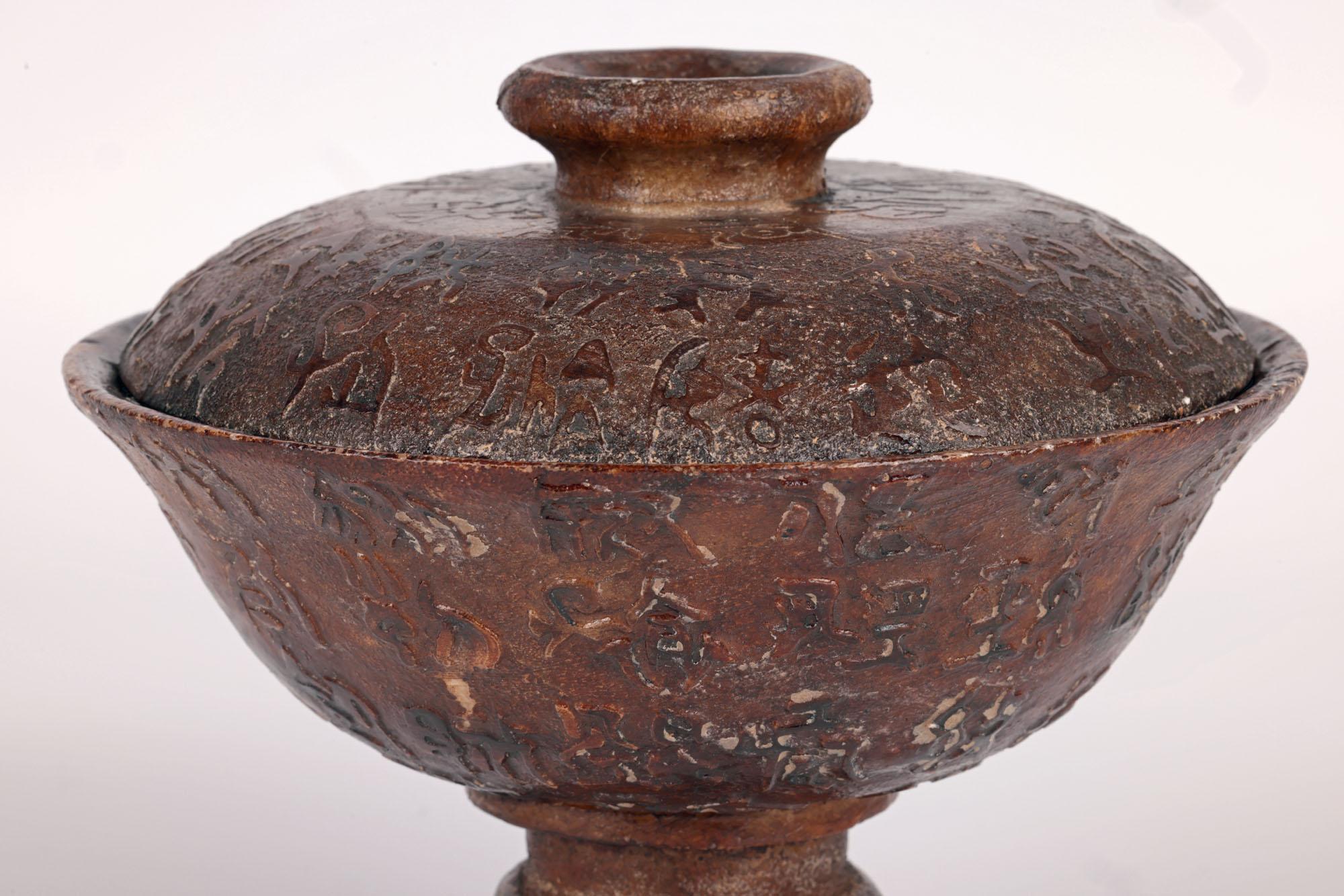An unusual Chinese archaic style script carved lidded stone vessel probably dating from the Qing dynasty or later. The heavily made vessel is made, we believe, from soapstone and comprises of a round bowl shaped pedestal base raised on a narrow