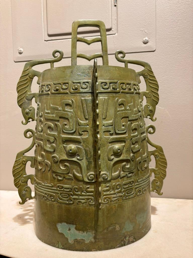 Chinese Archaistic bronze ritual bell with raised stylize tigers on the sides, a Taotie mask on front and back, incised and relief geometric decoration. With a wonderful olive green and verdigris patina. Large scale at 16 inches high, 12 wide, this