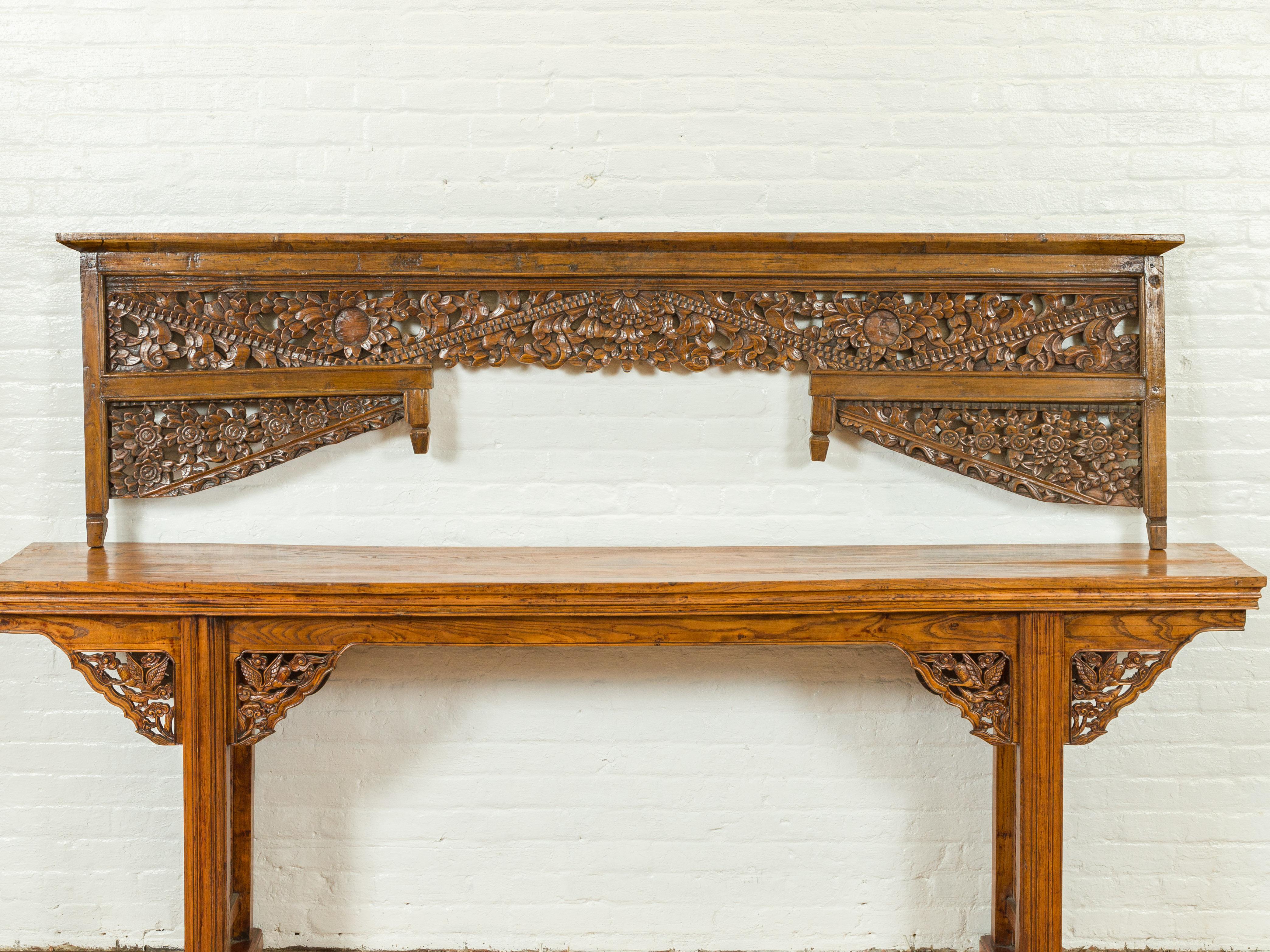 A Chinese architectural wood temple panel from the 19th century, with floral carvings. Attracting our attention with its skillfully executed motifs, this Chinese temple architectural panel features a simple cornice sitting above extremely detailed