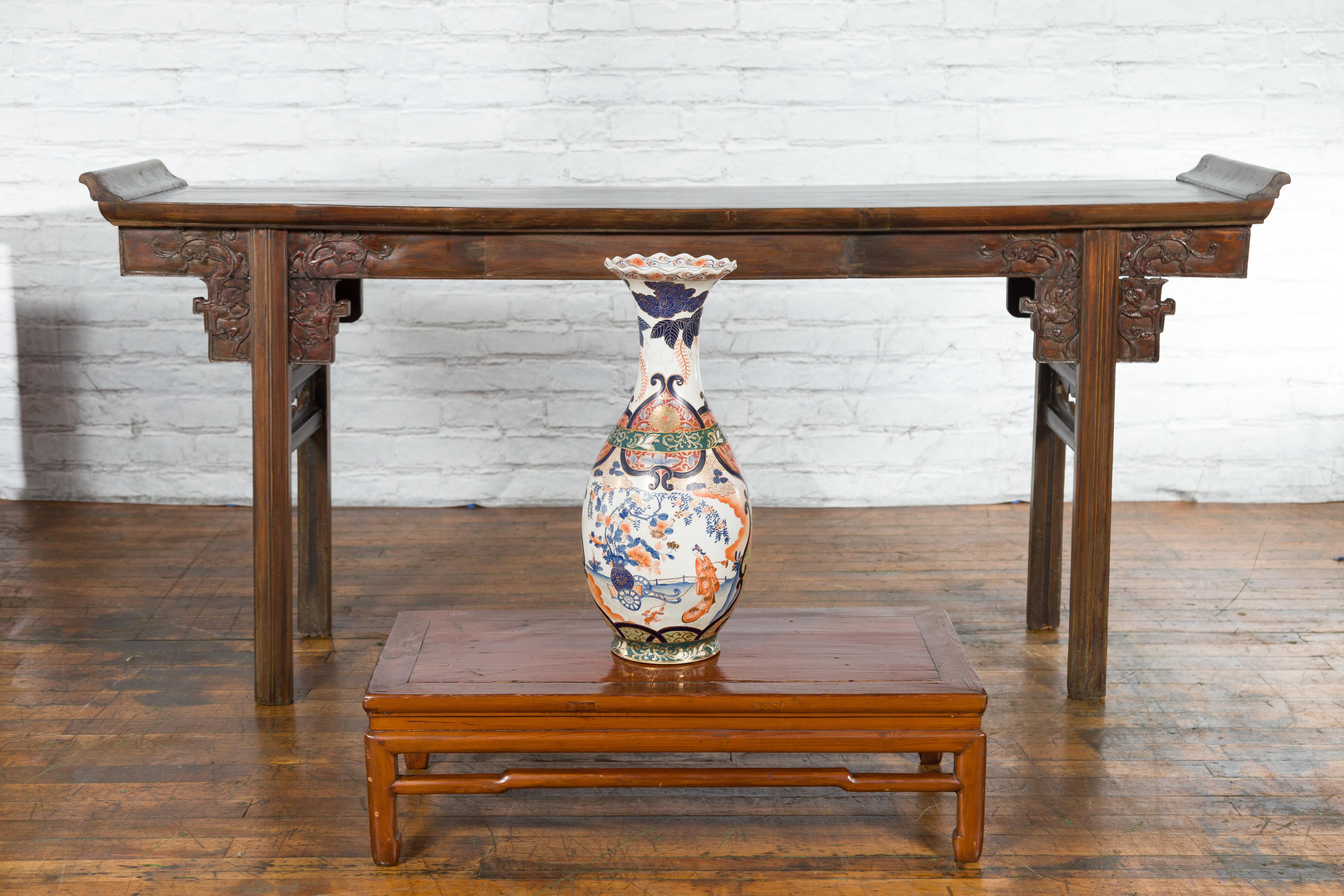 A Chinese vintage Imari style palace vase from the mid-20th century, with scalloped top, orange, blue and green décor as well as people, architecture and landscape motifs. Created in China during the Midcentury period, this Imari style palace vase