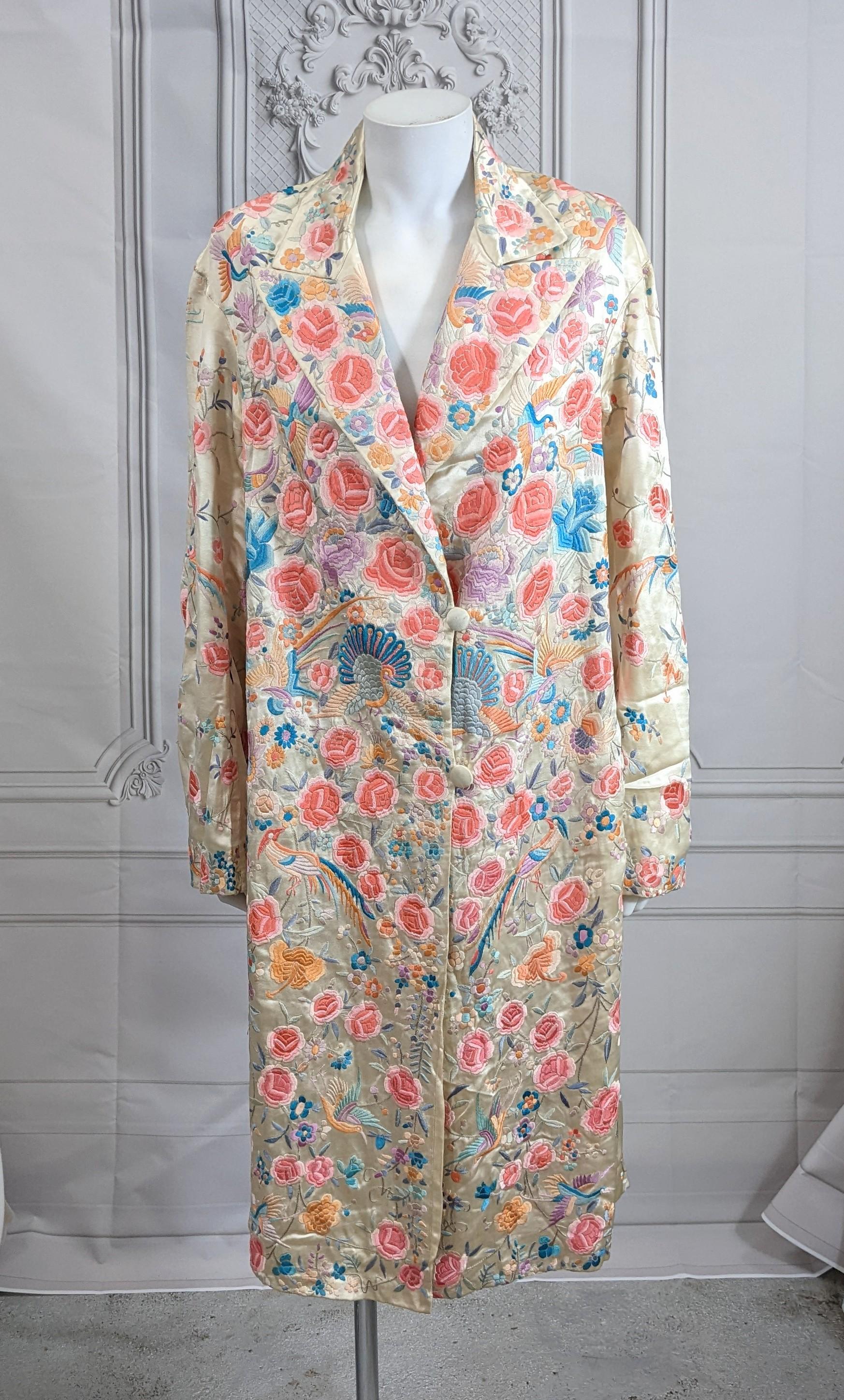 Chinese Art Deco Embroidered Coat with lavish pastel hand embroidered peacocks and birds amidst deep foliate patterns throughout. 2 button coat style with peak lapels on ivory china muslin with full china silk ivory lining. Loose cut with drop