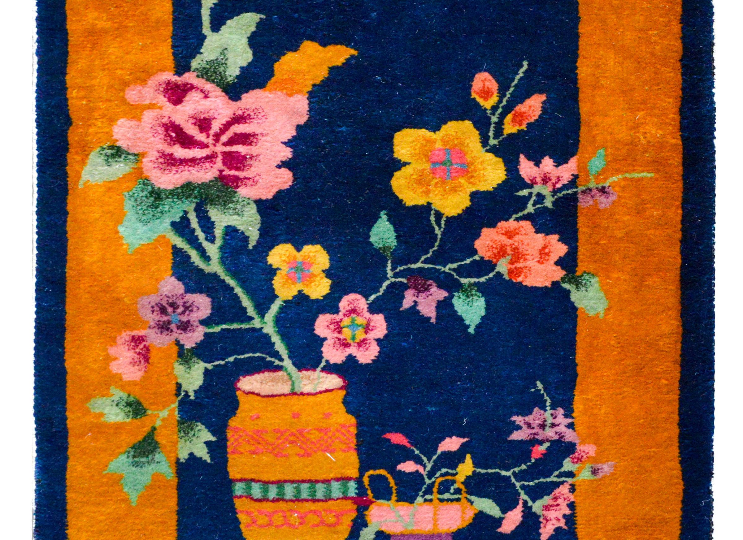 A Wonderfull early 20th century Chinese Art Deco rug with multi-colored peony and chrysanthemum plants each potted in a vase, and set against a dark indigo background and surrounded but a wide gold border.