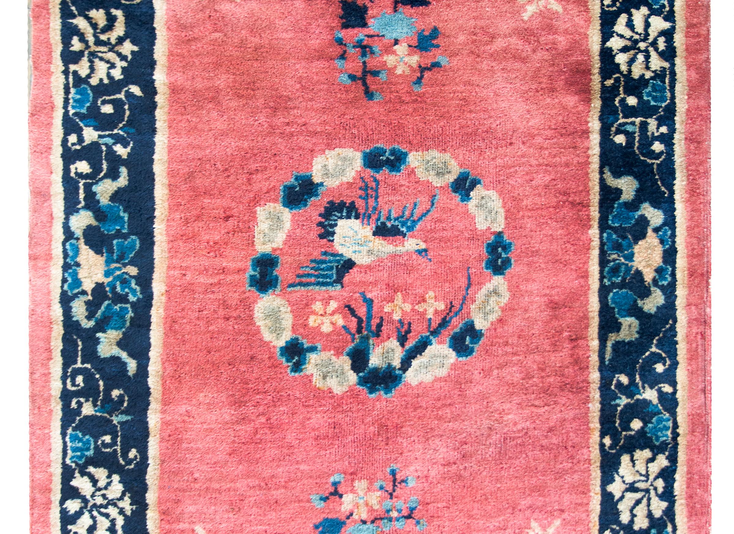 A wonderful early 20th century Chinese Art Deco rug with a central billowing cloud medallion surrounding a Phoenix, and living amidst a coral field with light and dark indigo peonies and cherry blossoms.  The border is sweet with even more