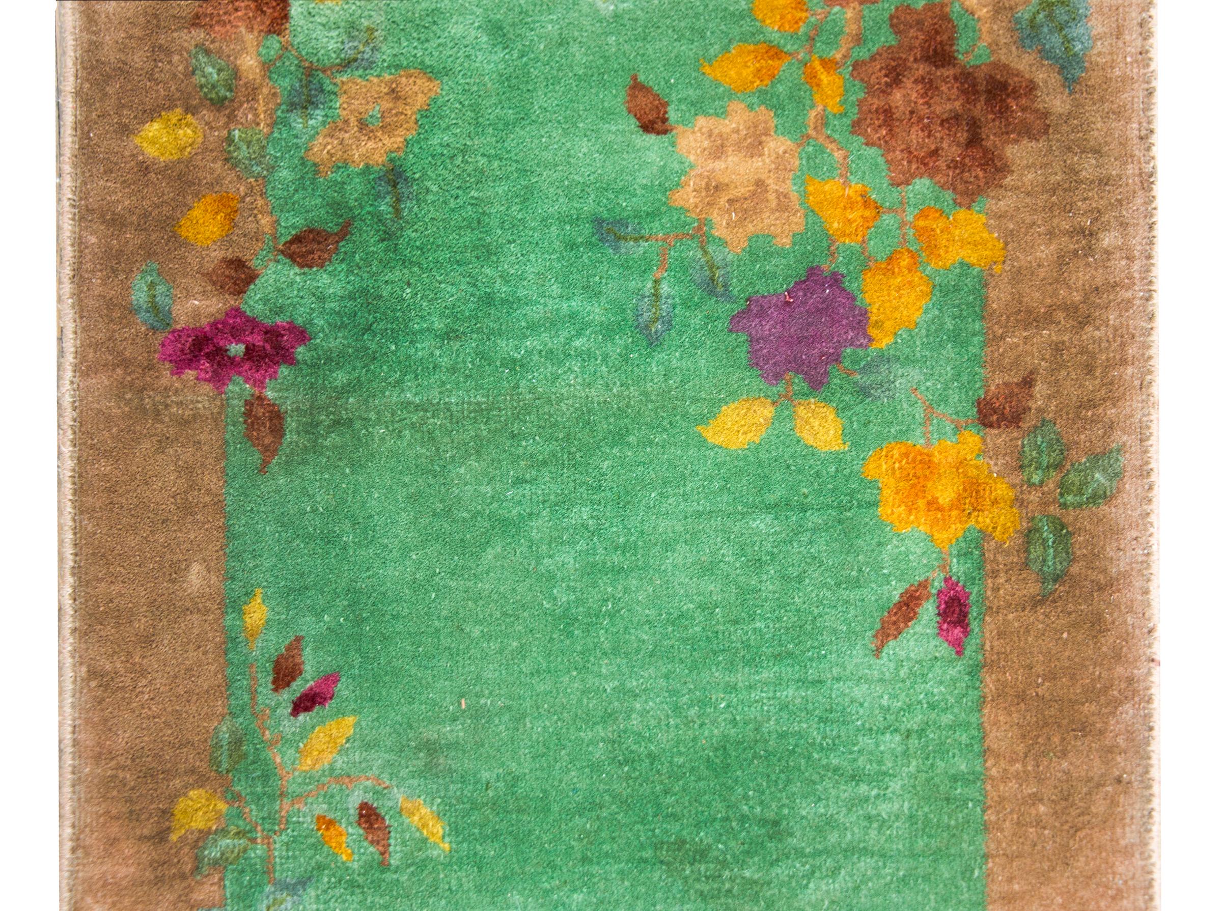 Un fantastique tapis chinois Art Déco du début du 20e siècle avec un champ vert menthe entouré d'une bordure ondulante beige sur laquelle sont incrustées des pivoines brunes, dorées, pêche et fuchsia.