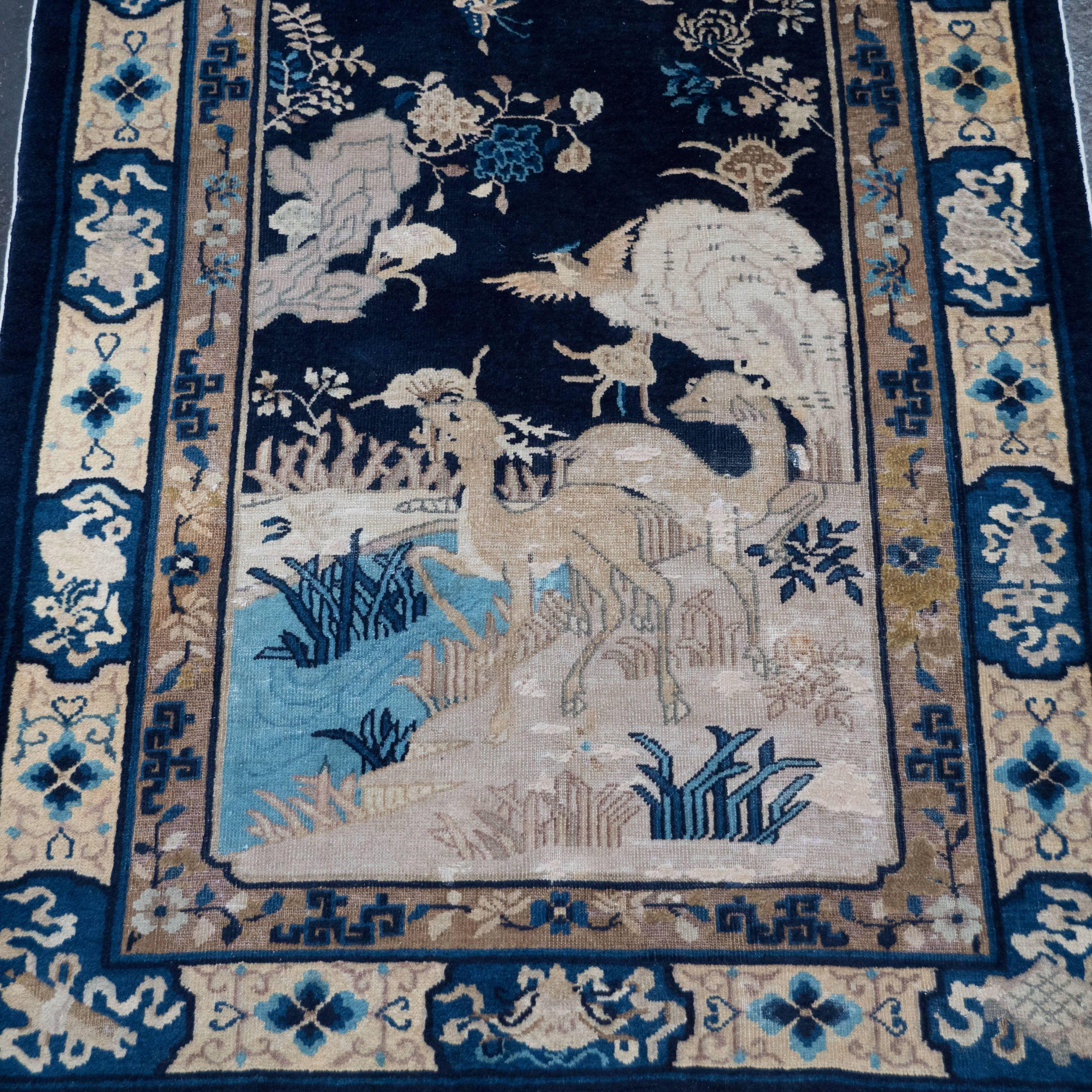 This beautiful hand-knotted Art Deco Chinoiserie rug was realized in China, circa 1925. It reflects the Western influence of Art Deco culture on traditional eastern crafts. The piece depicts a natural scene replete with deer, cranes, and an