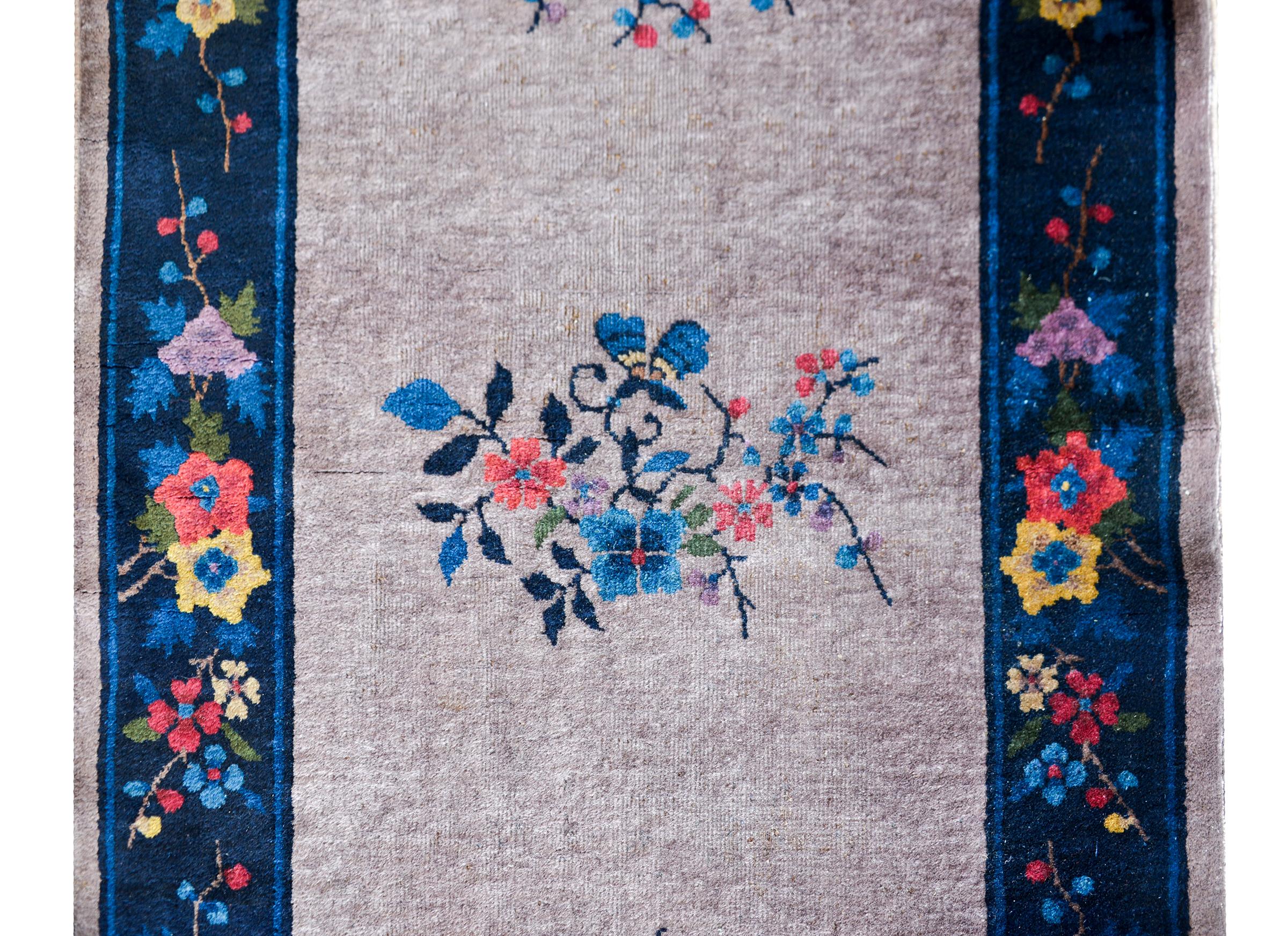A wonderful Chinese Art Deco runner with a gray field with five multi-colored cherry blossom medallions surrounded by an indigo border with more multi-colored auspicious flowers including lotus, peonies, and more cherry blossoms.