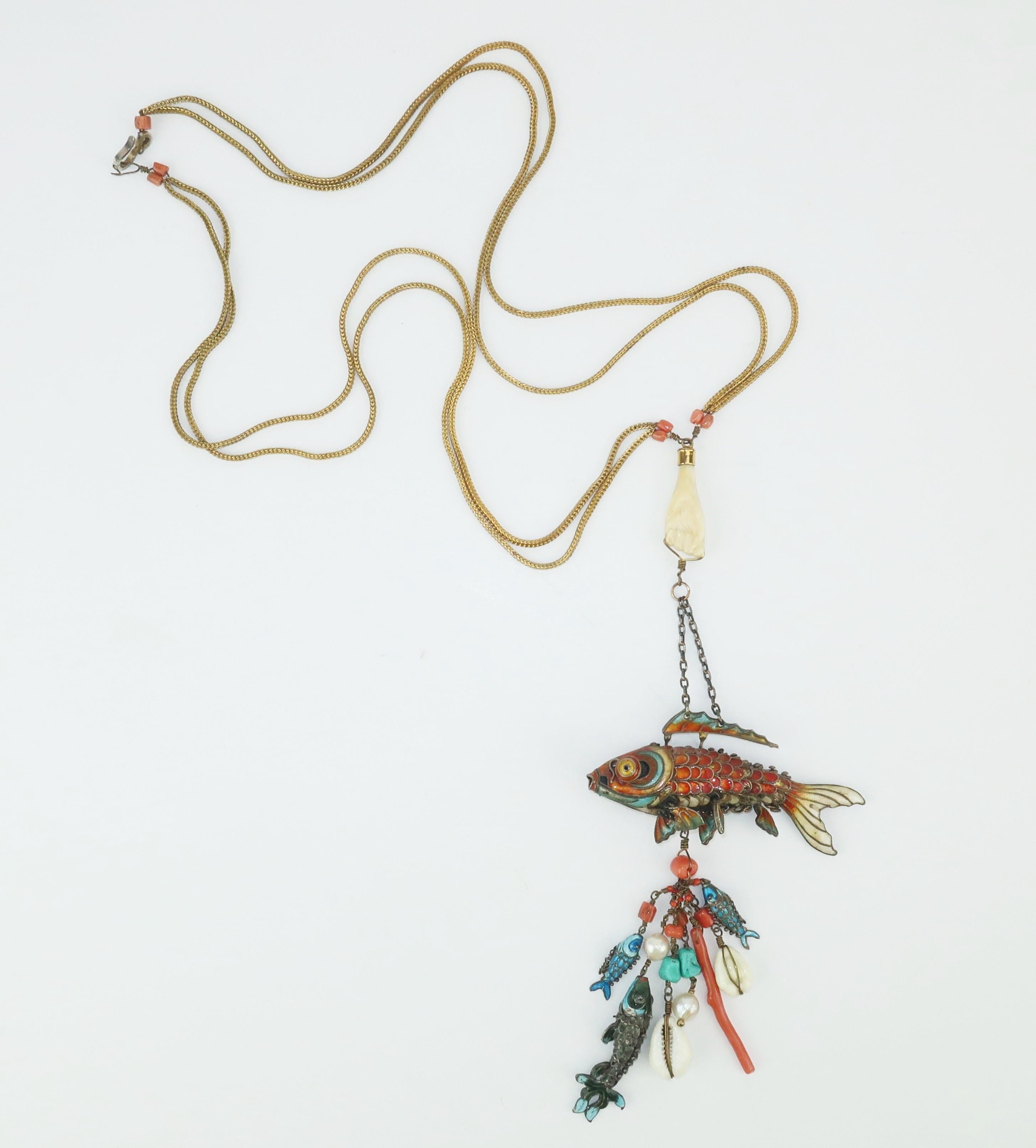 This fascinating mid 20th century Chinese necklace is a true work of art with a delicately carved bone hand suspending a large enamel articulated fish enhanced with dangles of coral, turquoise, pearls, shells and three smaller articulated fish.  The