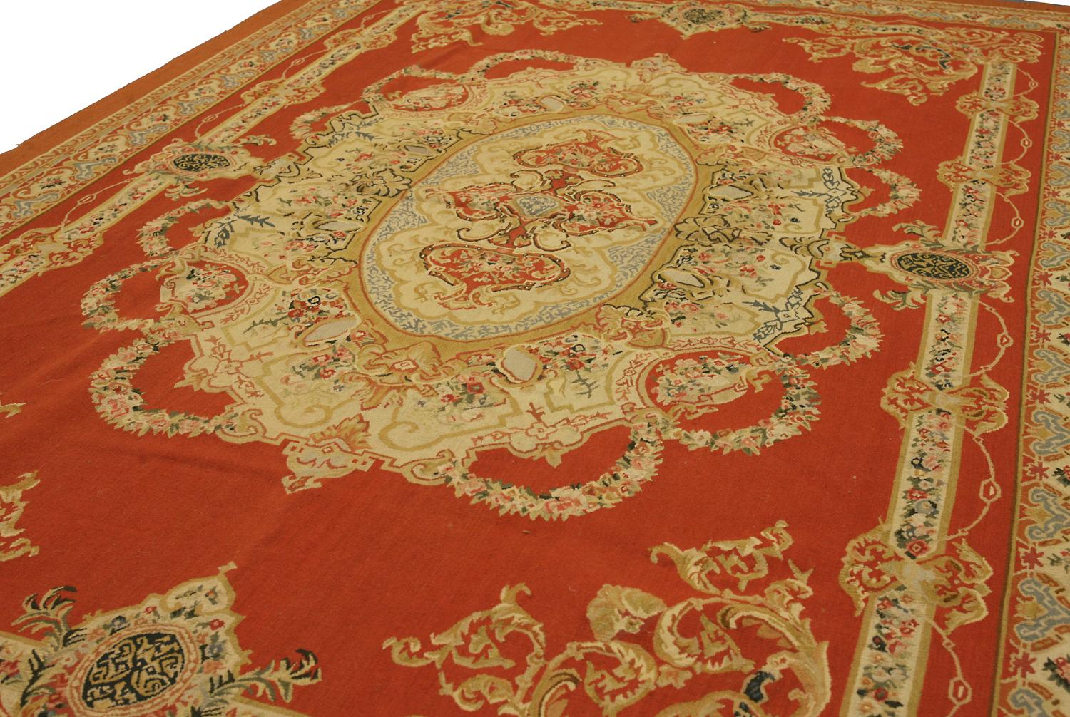 Il s'agit d'un magnifique tapis d'Aubusson à tissage plat, avec un médaillon et un motif floral. Il est parfait pour tous ceux qui veulent ajouter un peu d'élégance à leur maison. Le cadre de couleur ivoire sur le champ de briques rouges est