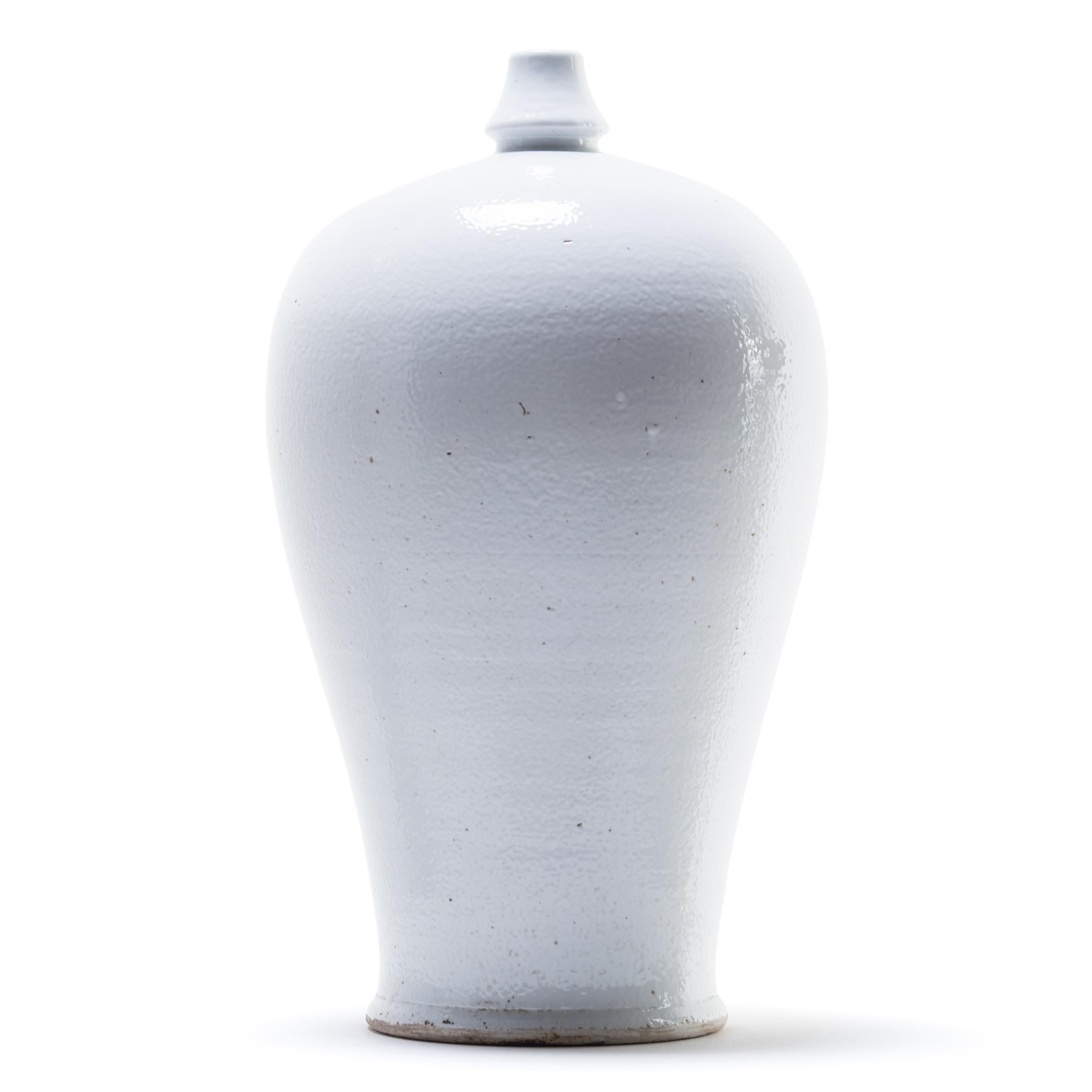 Meiping vases were traditionally used to hold the branches of plum trees, celebrated in China as symbols of strength. Made in China's Jiangxi province, this contemporary interpretation streamlines the form, cloaking it in a milky white glaze to call