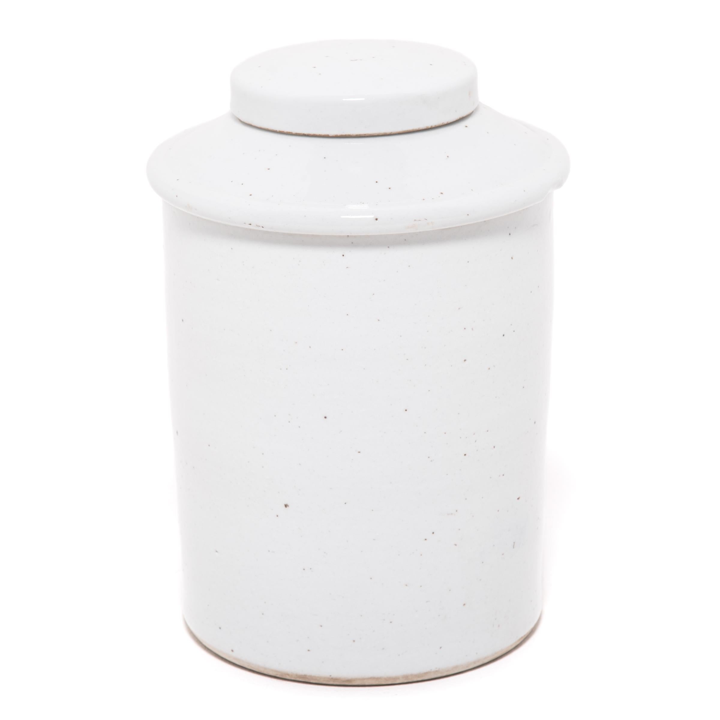 Rendue dans un glaçage blanc frappant, cette jarre contemporaine en porcelaine offre une interprétation moderne d'une forme classique. Les jarres à couvercle de ce type étaient utilisées dans les salons de thé en Chine, où la consommation de thé