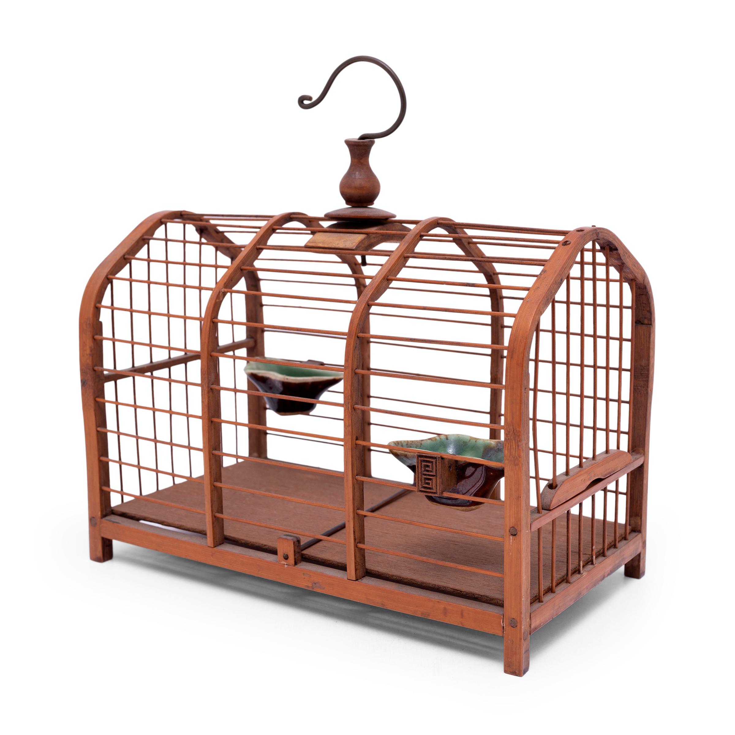 This petite bamboo birdcage was once home to the tiny pet bird of a Qing-dynasty aristocrat. Dated to the turn of the century, the birdcage is carefully assembled of thin bamboo rods set into an elongated frame with an adjustable opening at one end.