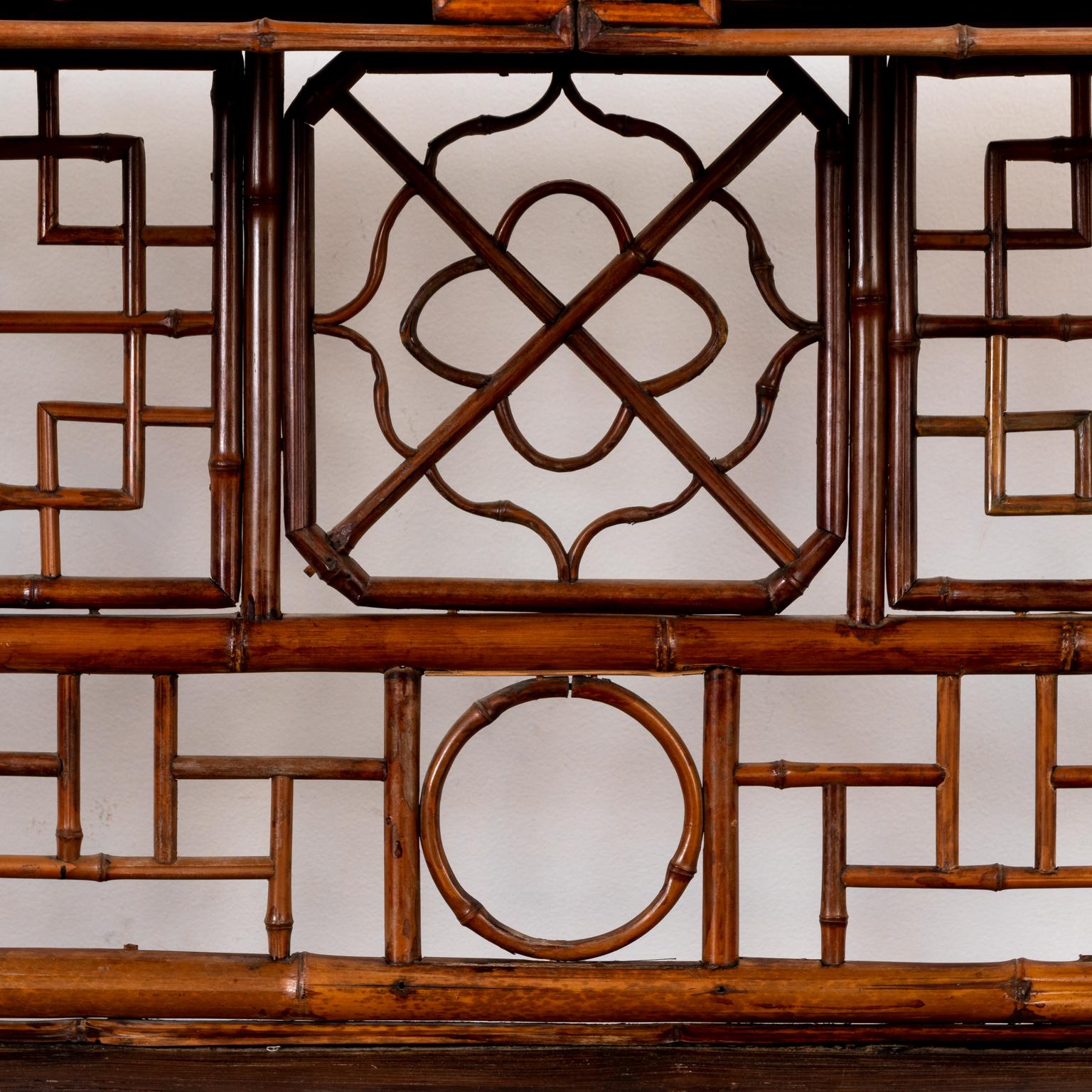 Circa 1960s Chinese bamboo etagere decorated with various geometric fretwork panels on the back and sides. Made in China. Please note of wear consistent with age including minor finish loss.