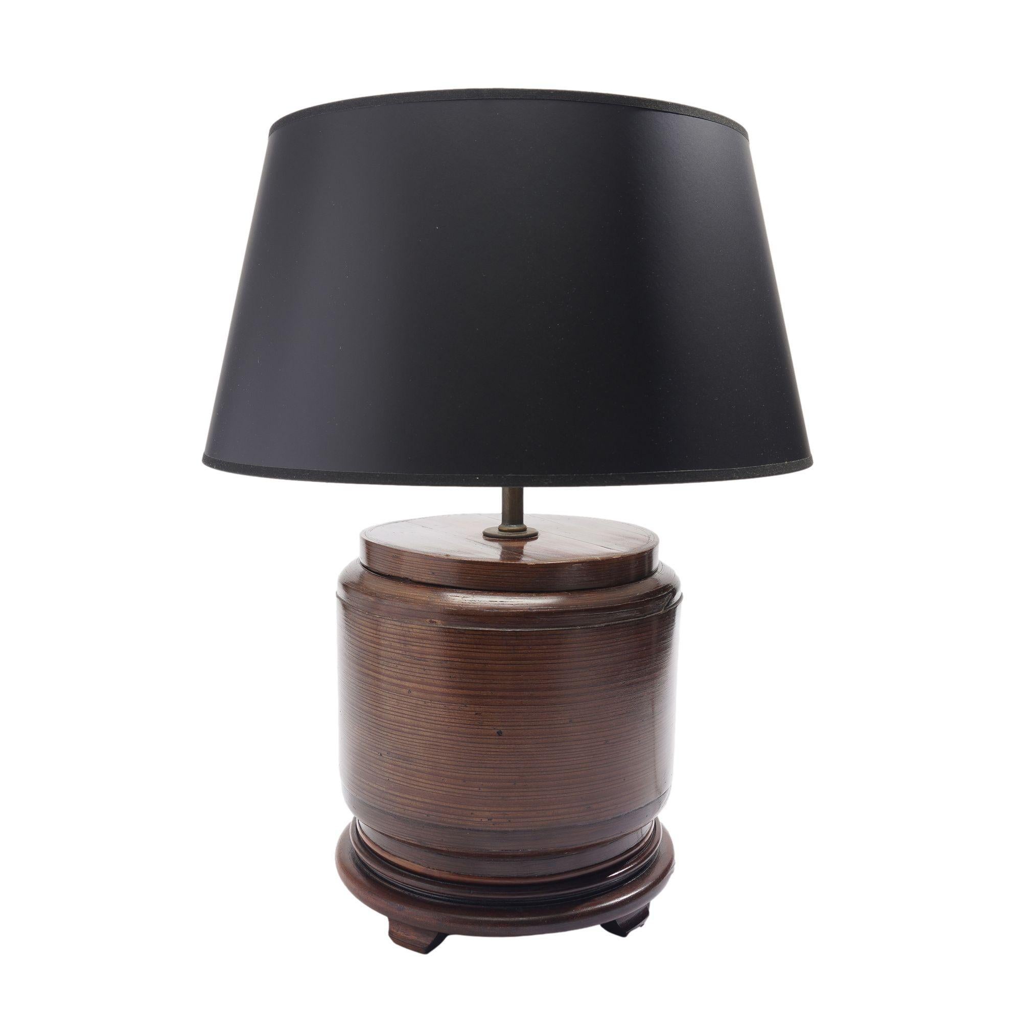 Chinese covered and footed rice box of bamboo with a sewn joint attachment, converted for use as a lamp. The surface retains its original lacquer finish and is mounted on a Chinese turned hardwood footed base. Shade not included.

China, early