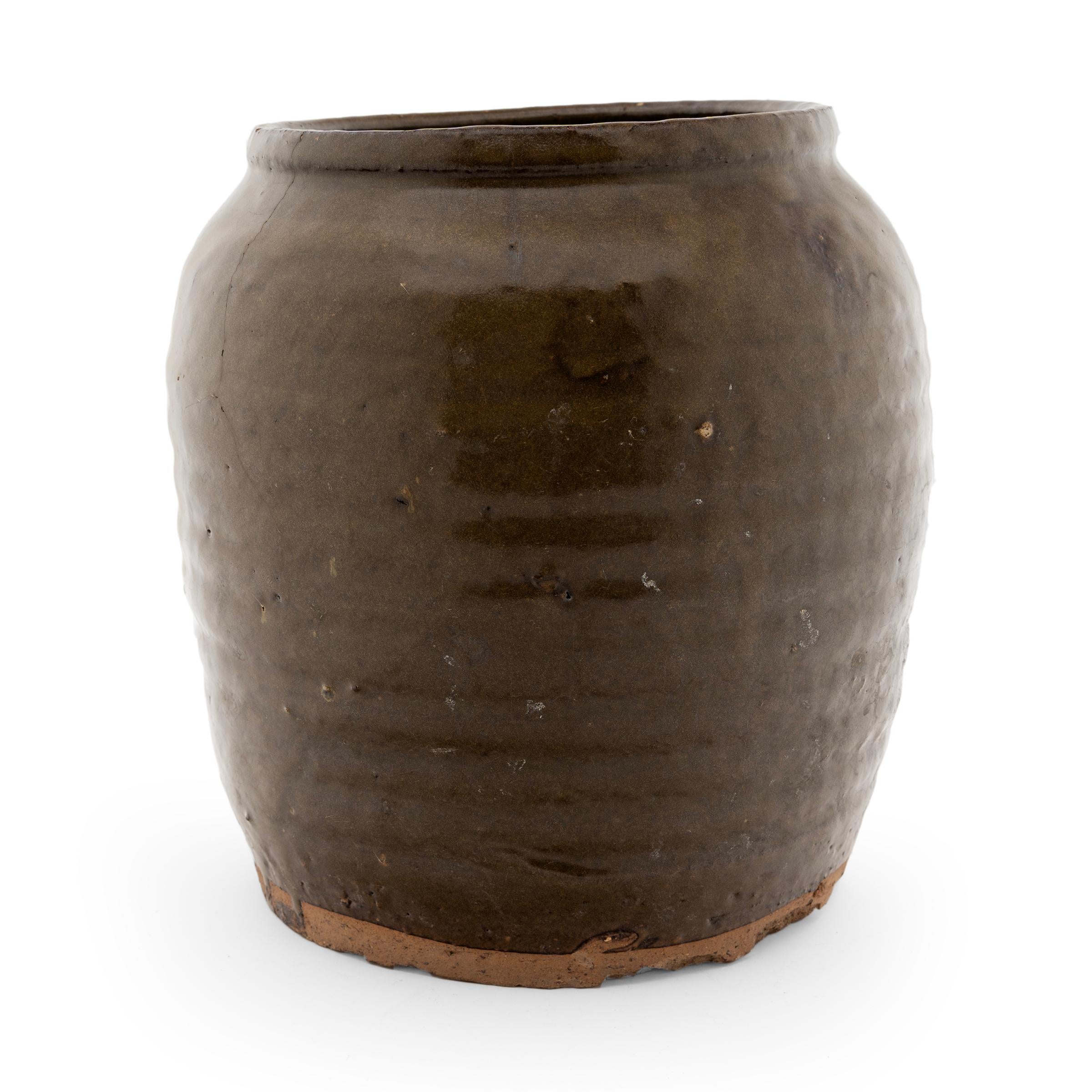 Opaque brown glaze cloaks the stout body of this early 20th-century terra cotta kitchen jar. As evidenced by the glazed interior, this wide-mouth jar was used in a provincial Chinese kitchen for fermenting foods and condiments. The slightly tapered