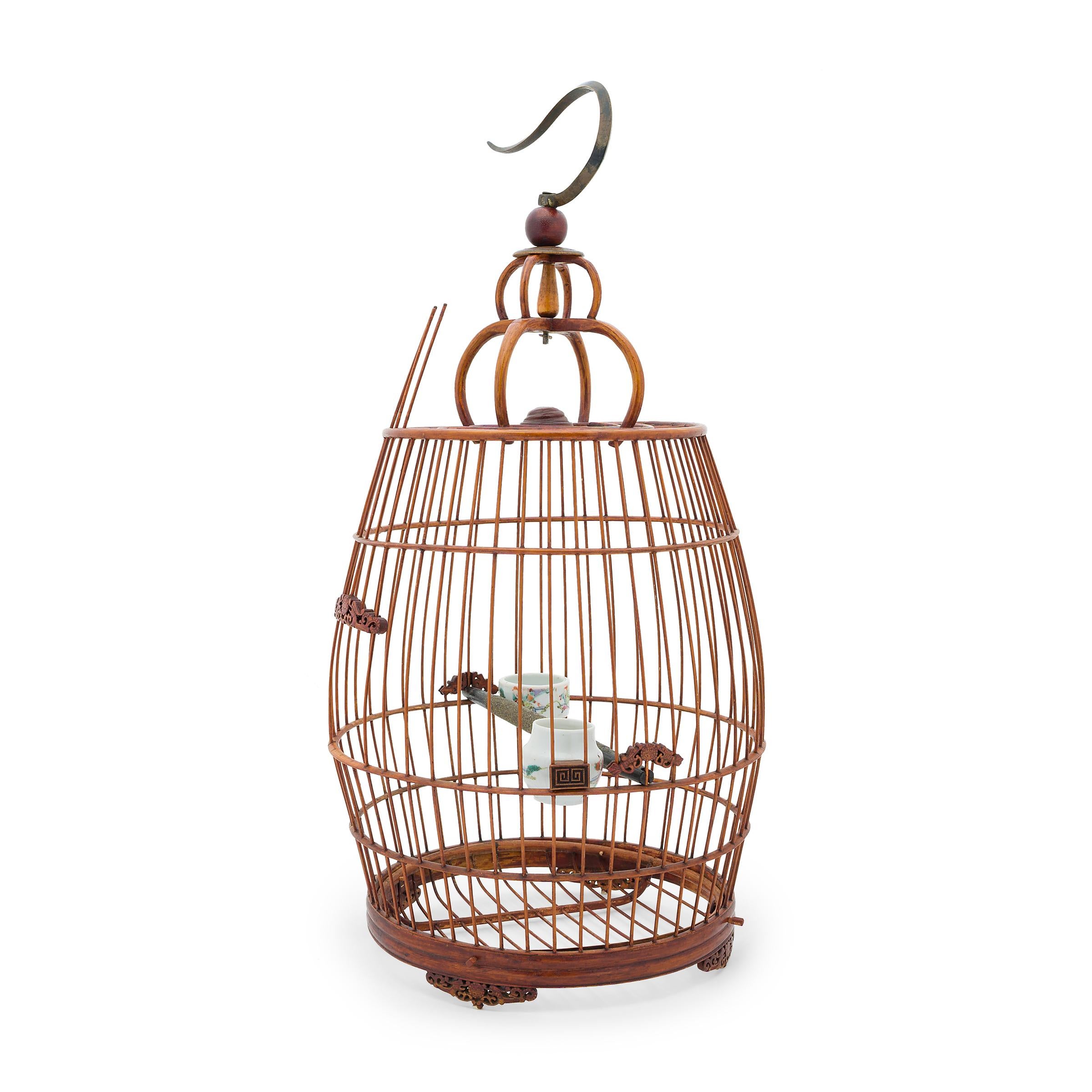 This large wooden birdcage was once home to the tiny pet bird of a Qing-dynasty aristocrat. Dated to the early 20th century, this barrel-form cage is carefully assembled of thin bamboo rods set within a bent bamboo frame. Small fretwork carvings