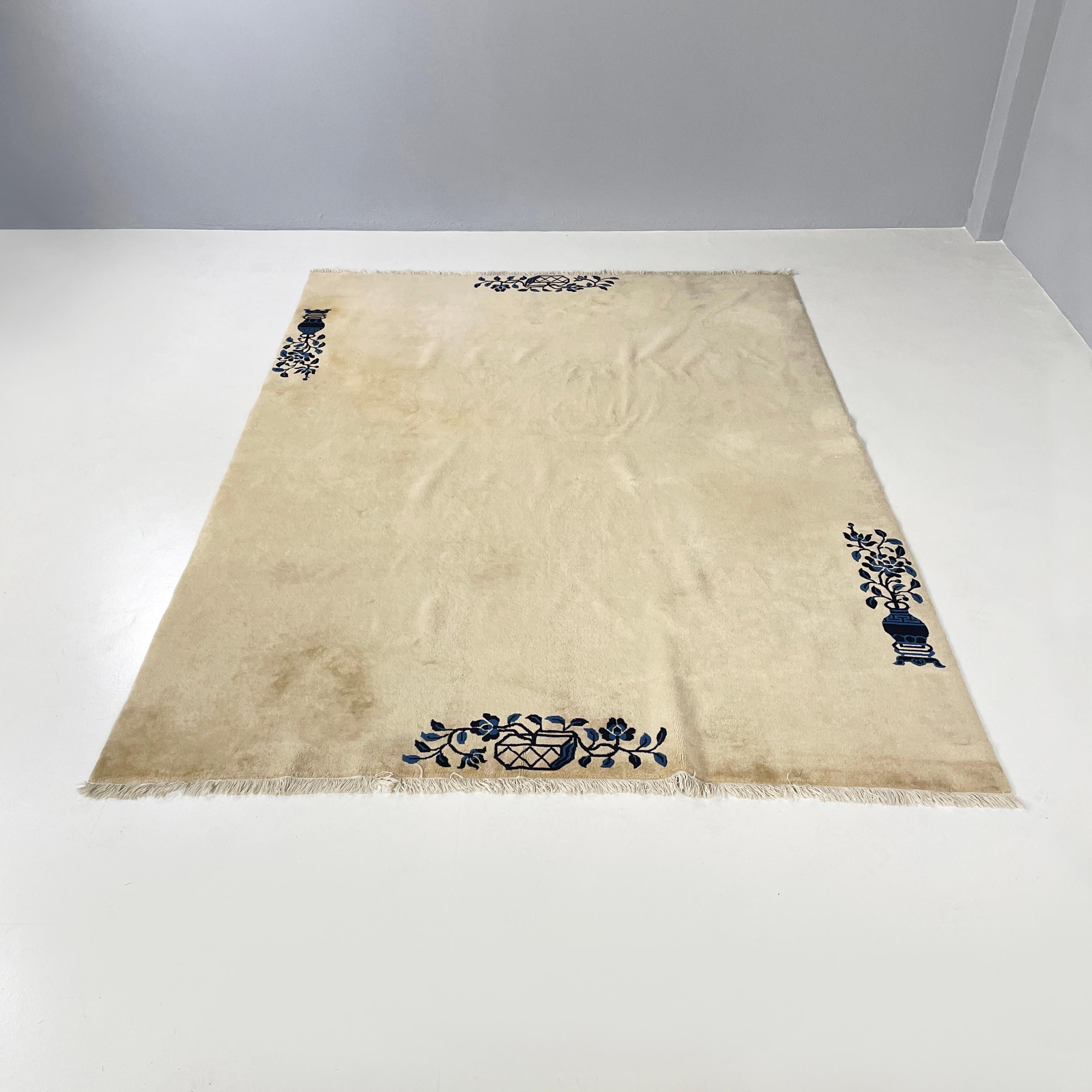 Chinesischer beiger Teppich mit schwarzem und blauem Blumendekor, Anfang 1900
Rechteckiger Teppich in Beigetönen mit schwarzen und blauen Verzierungen. Die Verzierungen auf dem Profil stellen zwei Blumenvasen dar: eine schmale und hohe und eine