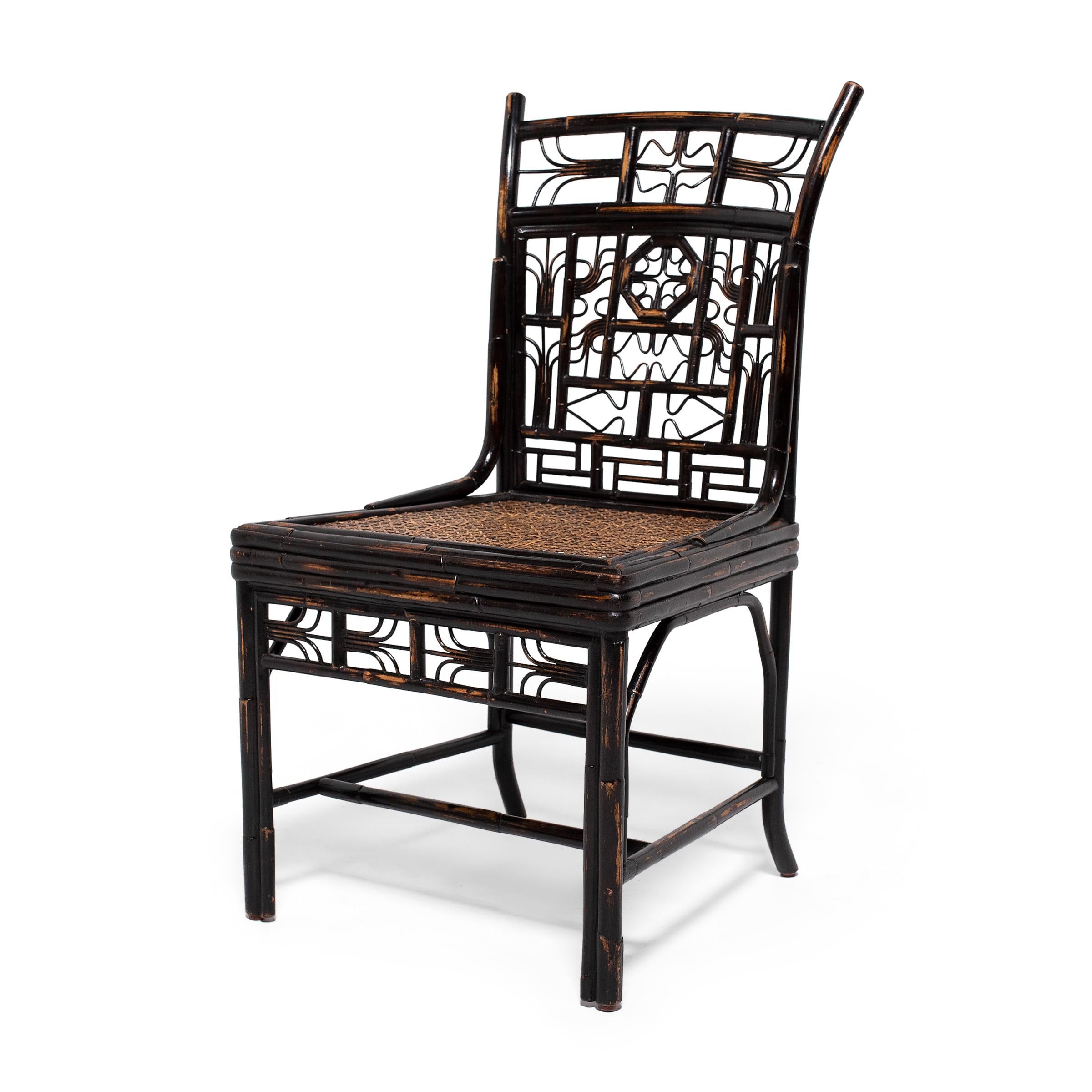 Dated to the early 20th century, this captivating dining chair is crafted of bamboo that has been carefully steamed and bent into elaborate forms. The chair features a square woven cane seat and a geometric bamboo frame embellished with lattice-like
