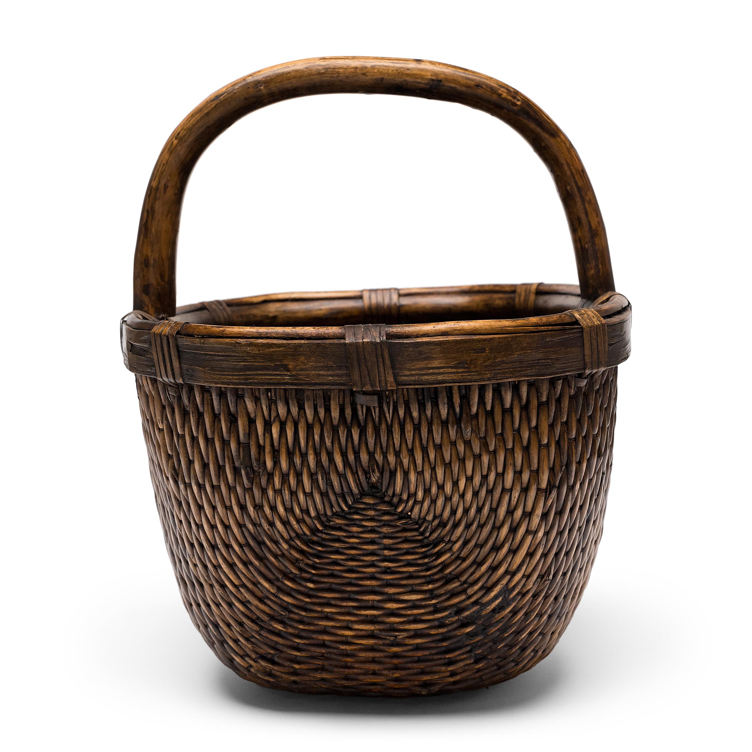 It is easy to imagine someone, long ago, gathering a harvest from their garden or strolling to the market with this beautiful basket tucked under their arm. The oval basket has been artfully woven by hand of willow and cord around a bent bamboo rim,