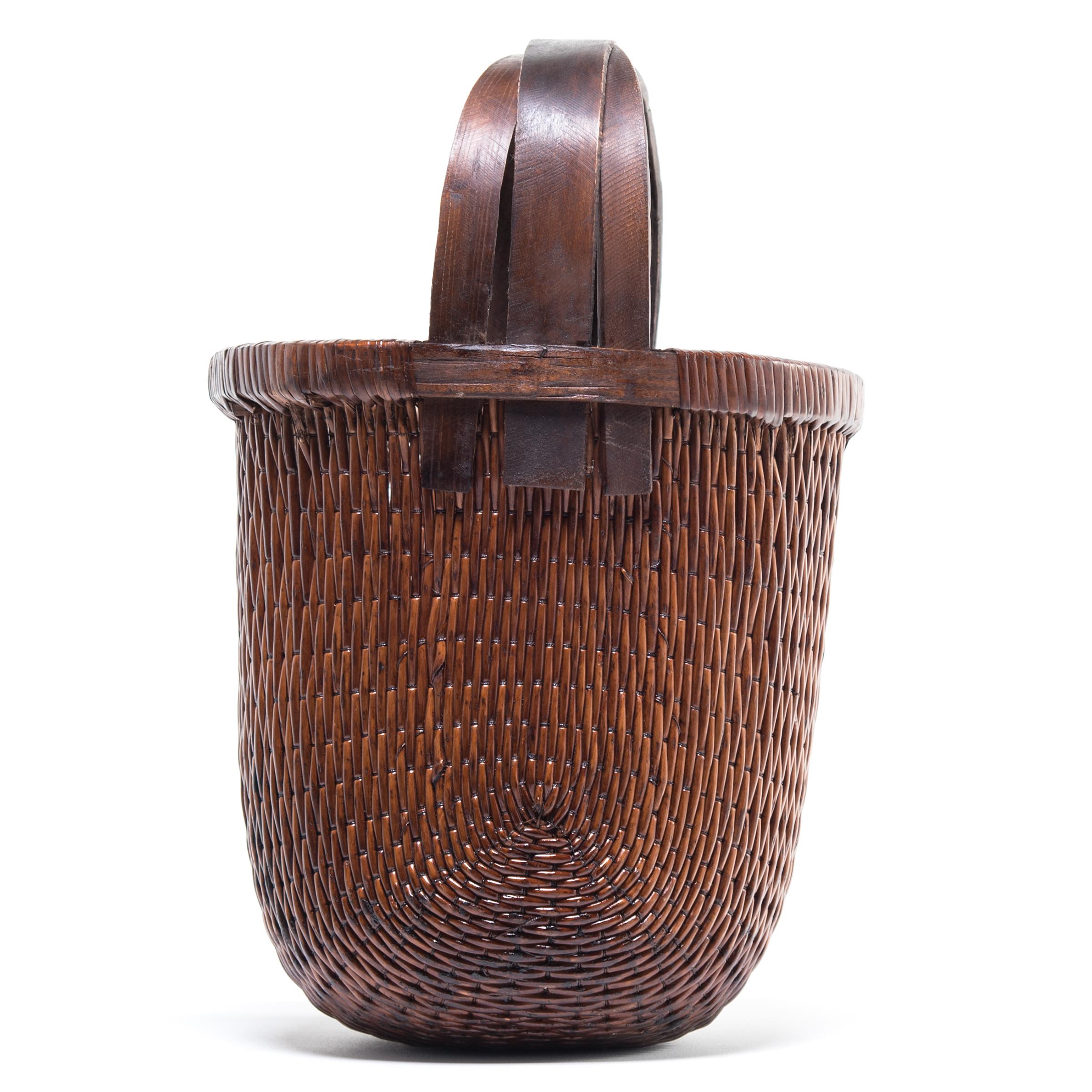 Basket making is an ancient and humble craft, but in the hands of a skilled weaver a simple willow basket can become a truly beautiful work of art. This bent handle basket was made in China long ago, and the artisan’s mastery is evident: the strong,