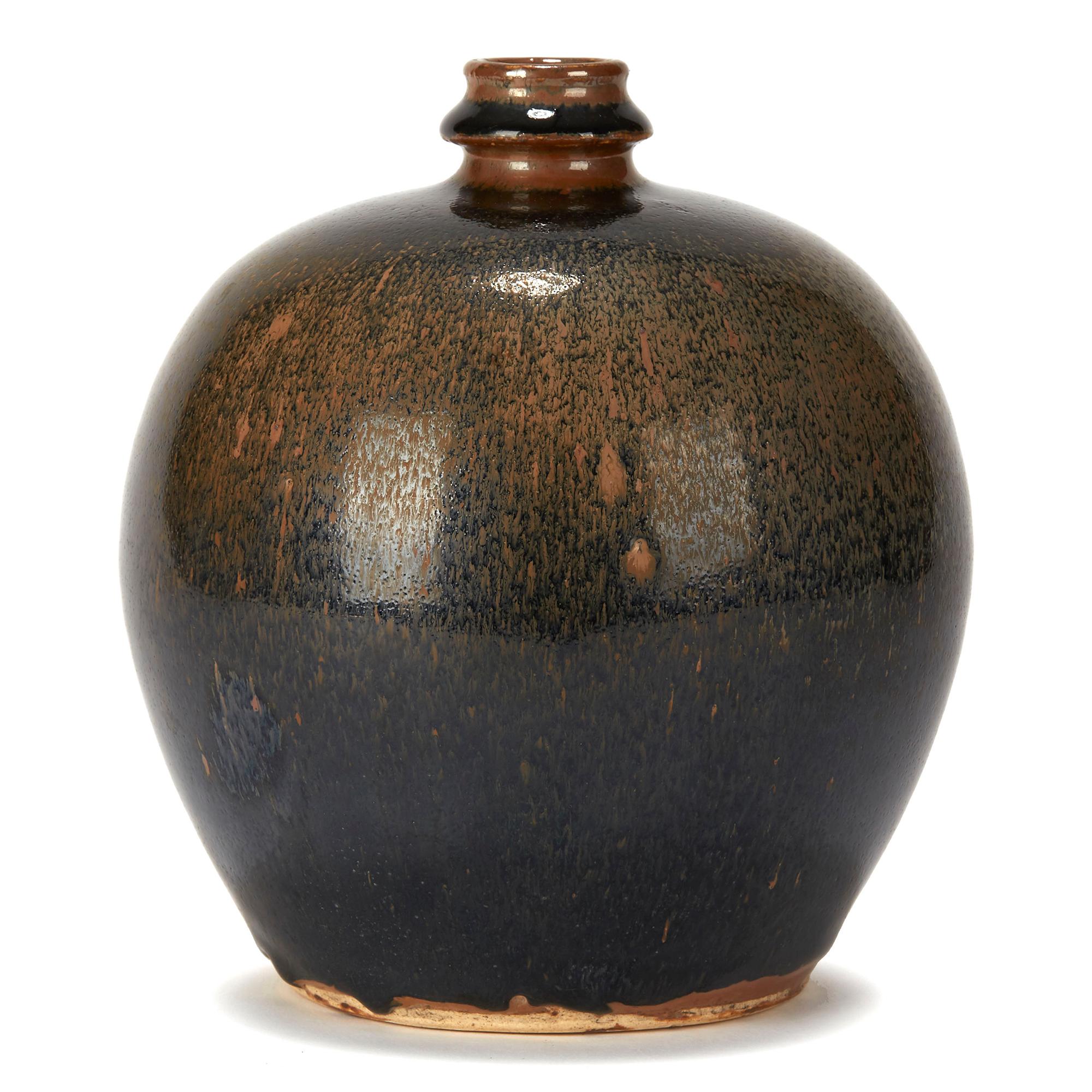 A stylish Chinese art pottery vase of rounded bulbous shape with a bottle shaped neck and opening and decorated in black haresfur style glaze on a brown ground. The vase has an unglazed foot and base and is not marked.

OR19188.