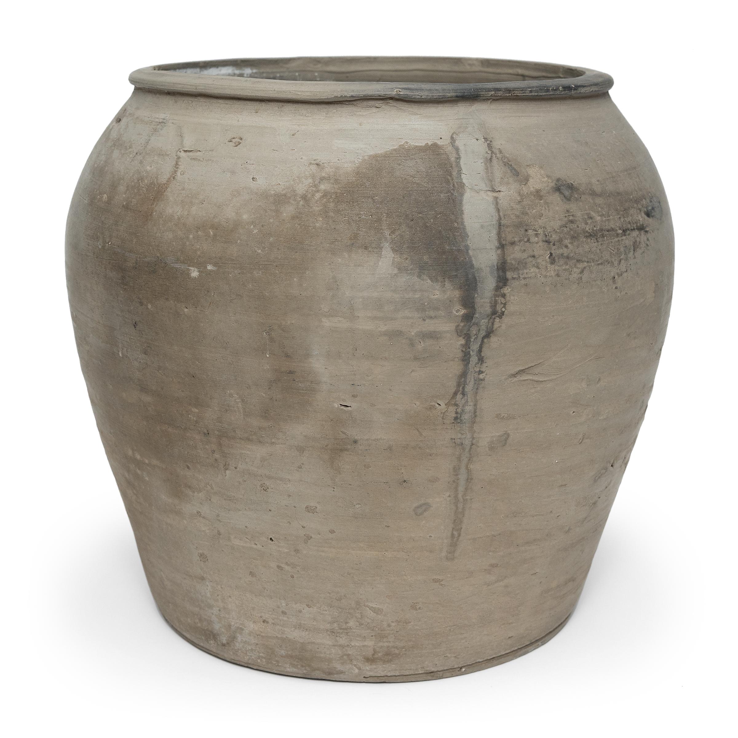 Sculpted during the early 20th century in China's Shanxi province, this vessel has a mottled grey exterior with balanced proportions and a beautifully irregular unglazed surface. Charged with the humble task of storing dry goods, this earthenware